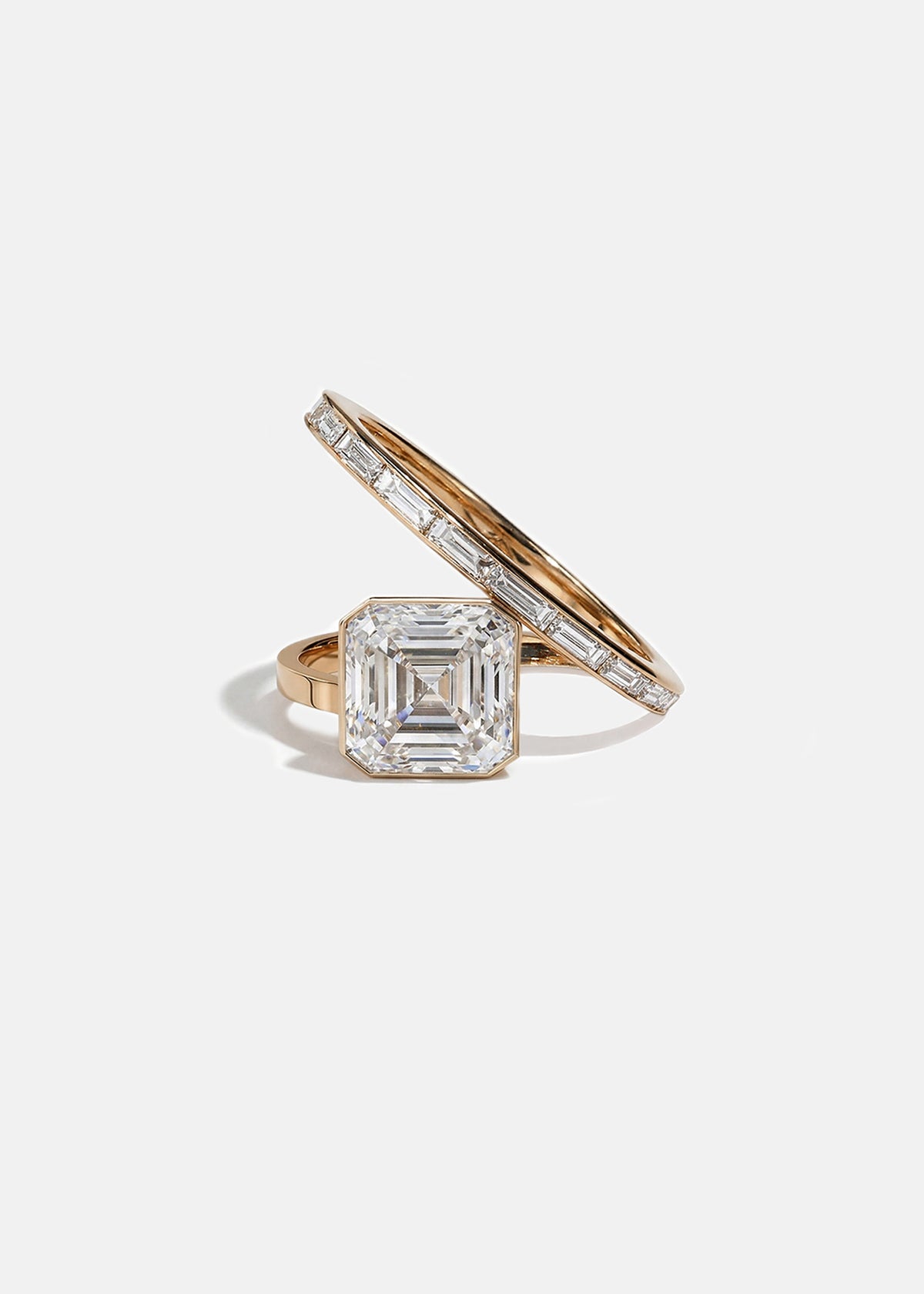 18k rose gold bypass ring featuring a floating asscher cut diamond and tapering channel of baguettes band.