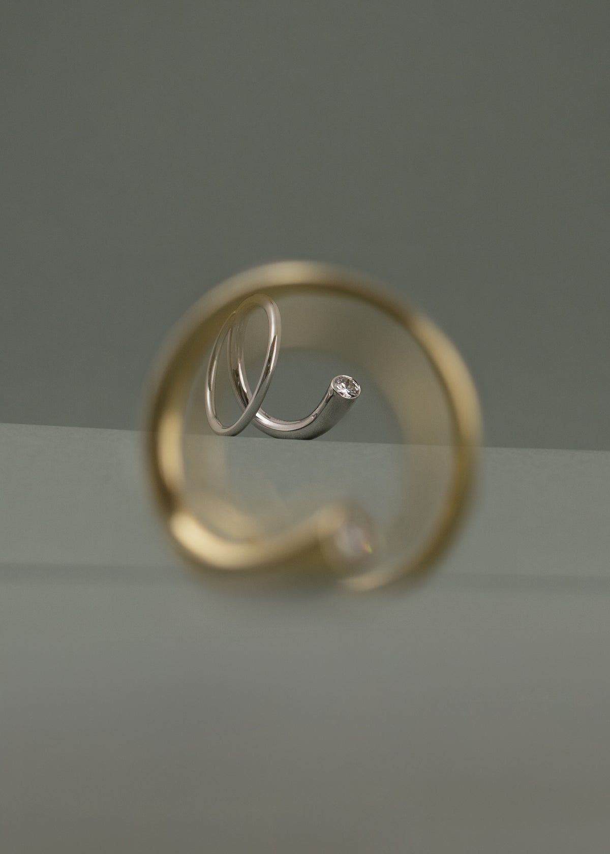 yellow gold crescendo ring in the blurry foreground and a white gold crescendo ring in focus in depth