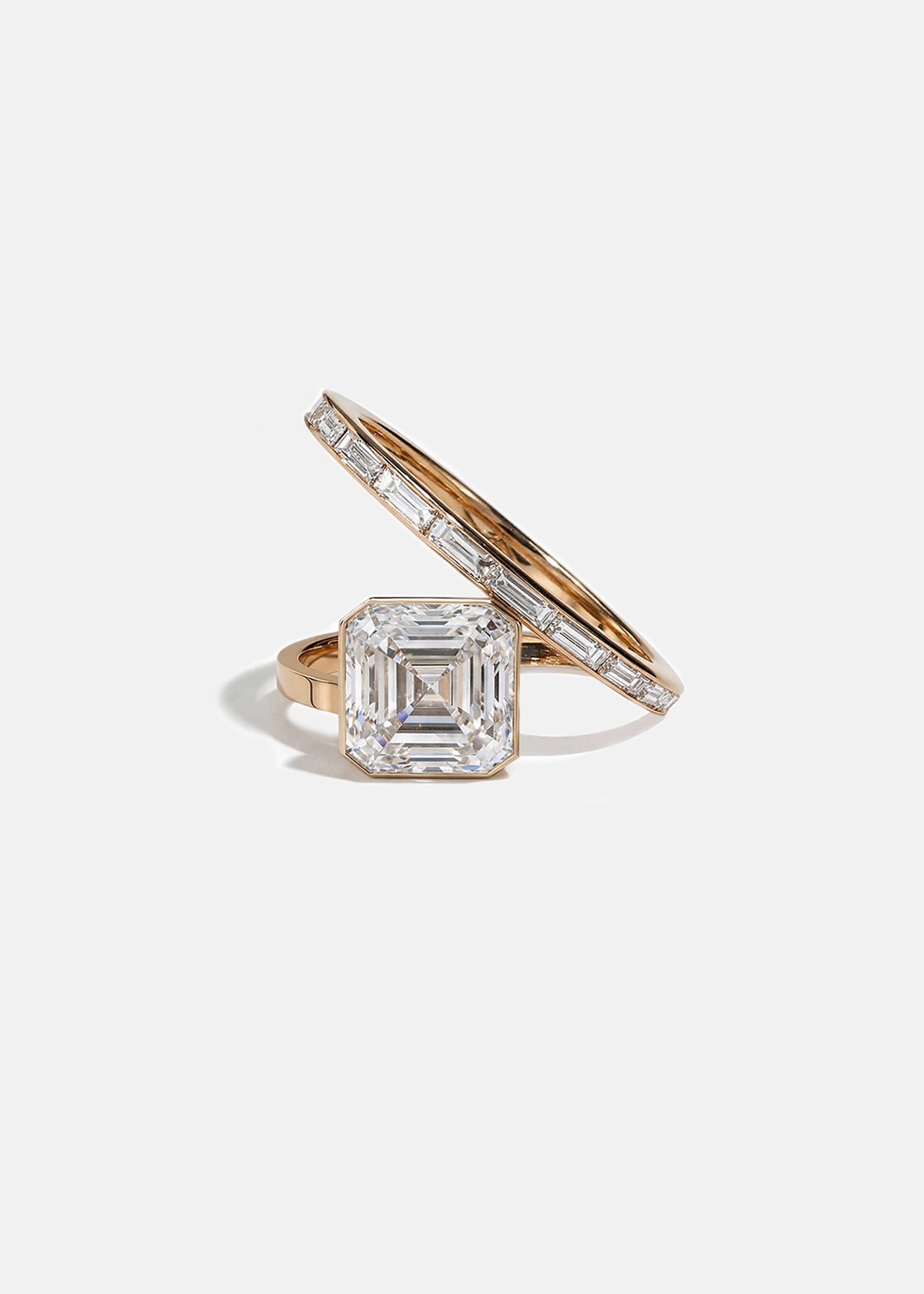 18k rose gold bypass ring featuring a floating asscher cut diamond and tapering channel of baguettes band.