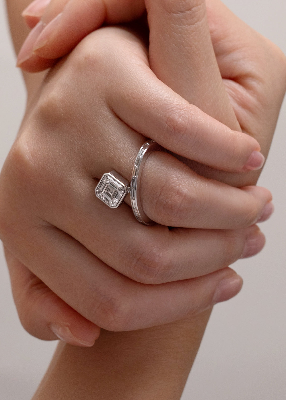 worn on the ring finger-18k white gold bypass ring featuring a floating asscher cut diamond and tapering channel of baguettes band.