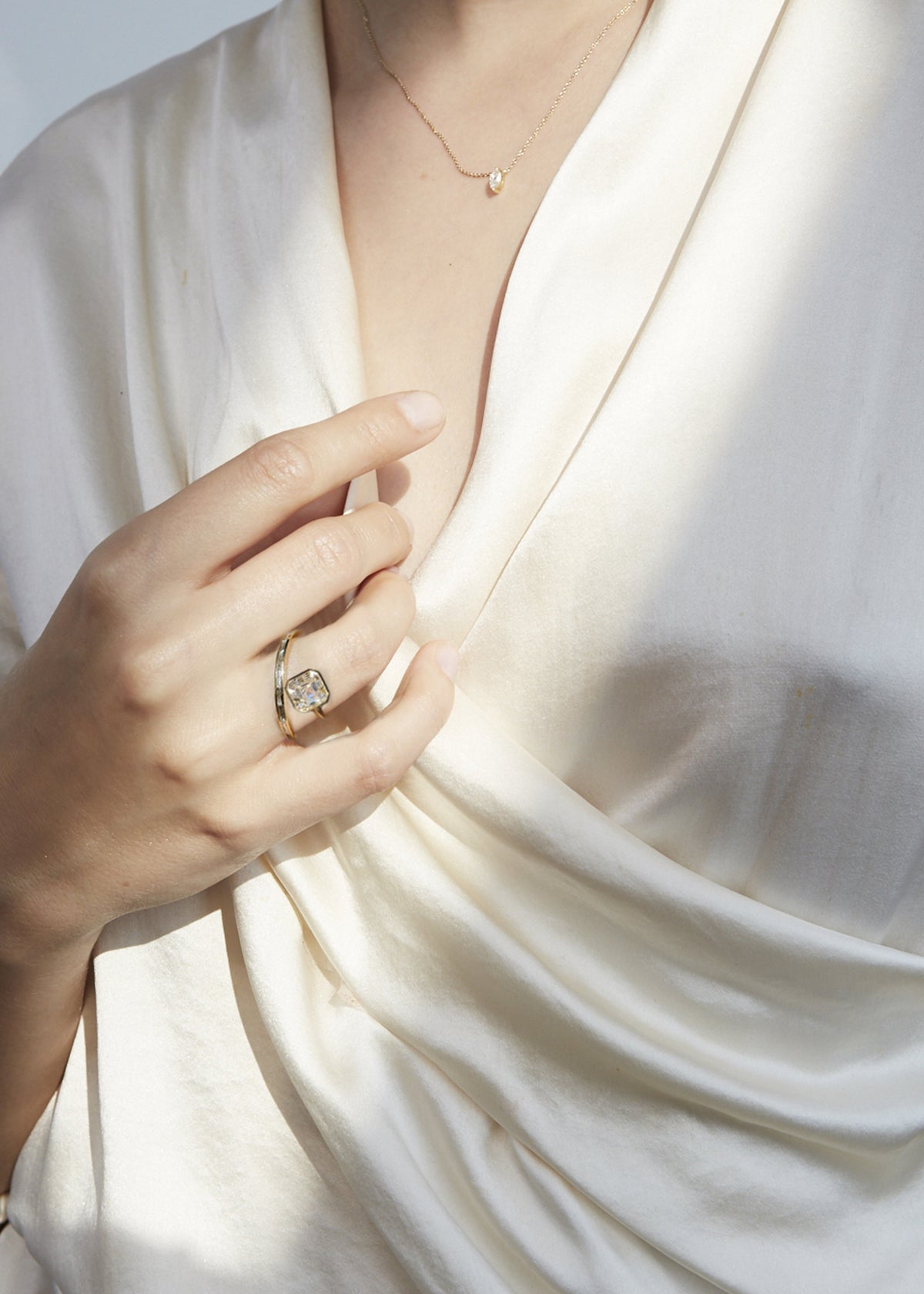 model wearing 18k yellow gold bypass ring featuring a floating asscher cut diamond and tapering channel of baguettes band.
