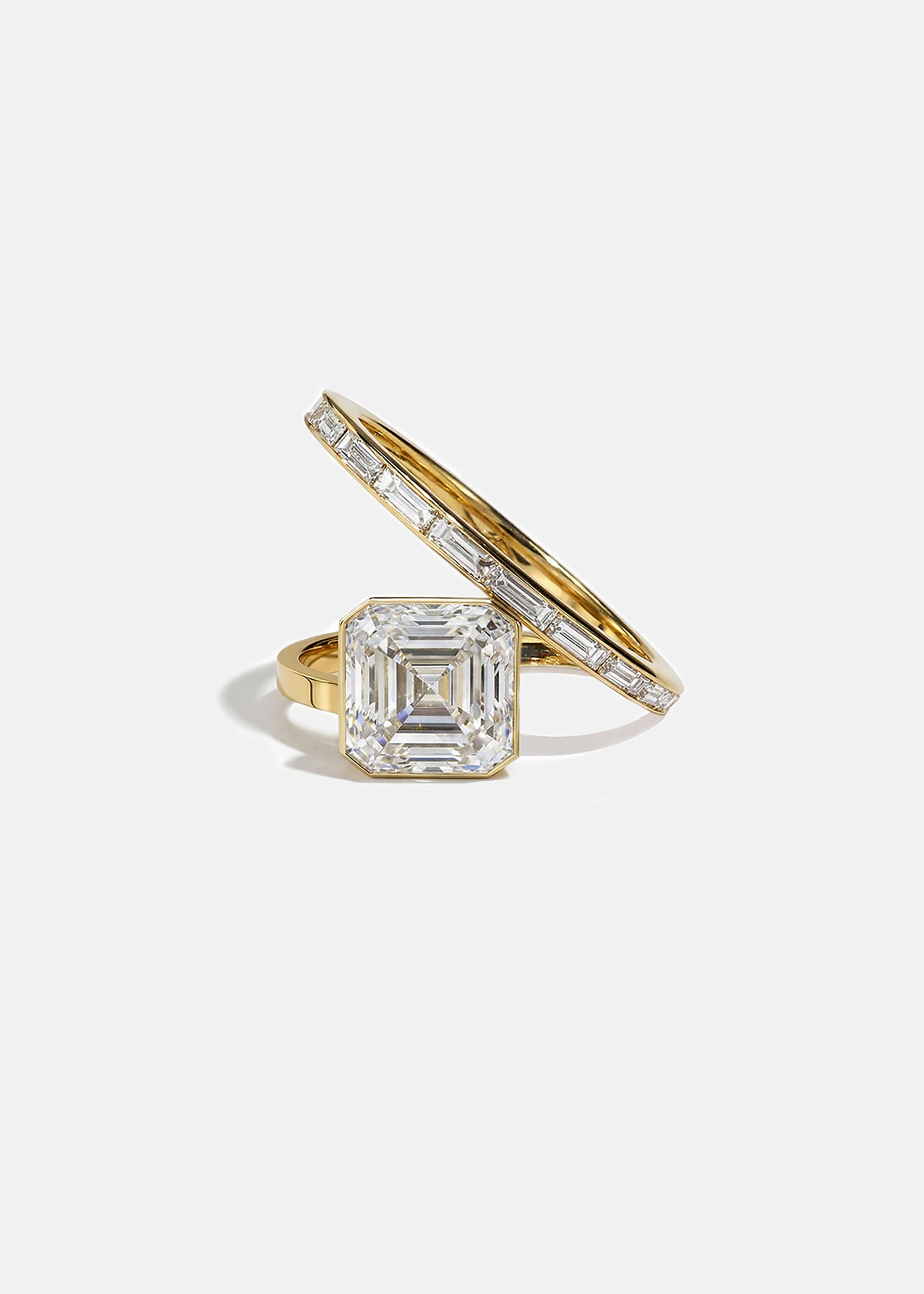 18k yellow gold bypass ring featuring a floating asscher cut diamond and tapering channel of baguettes band.