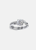 close up of  a stack of 18k white gold solitaire engagement ring featuring a floating round brilliantl diamond on a fluid, tapering open band with a round cut diamond on a white gold open band.