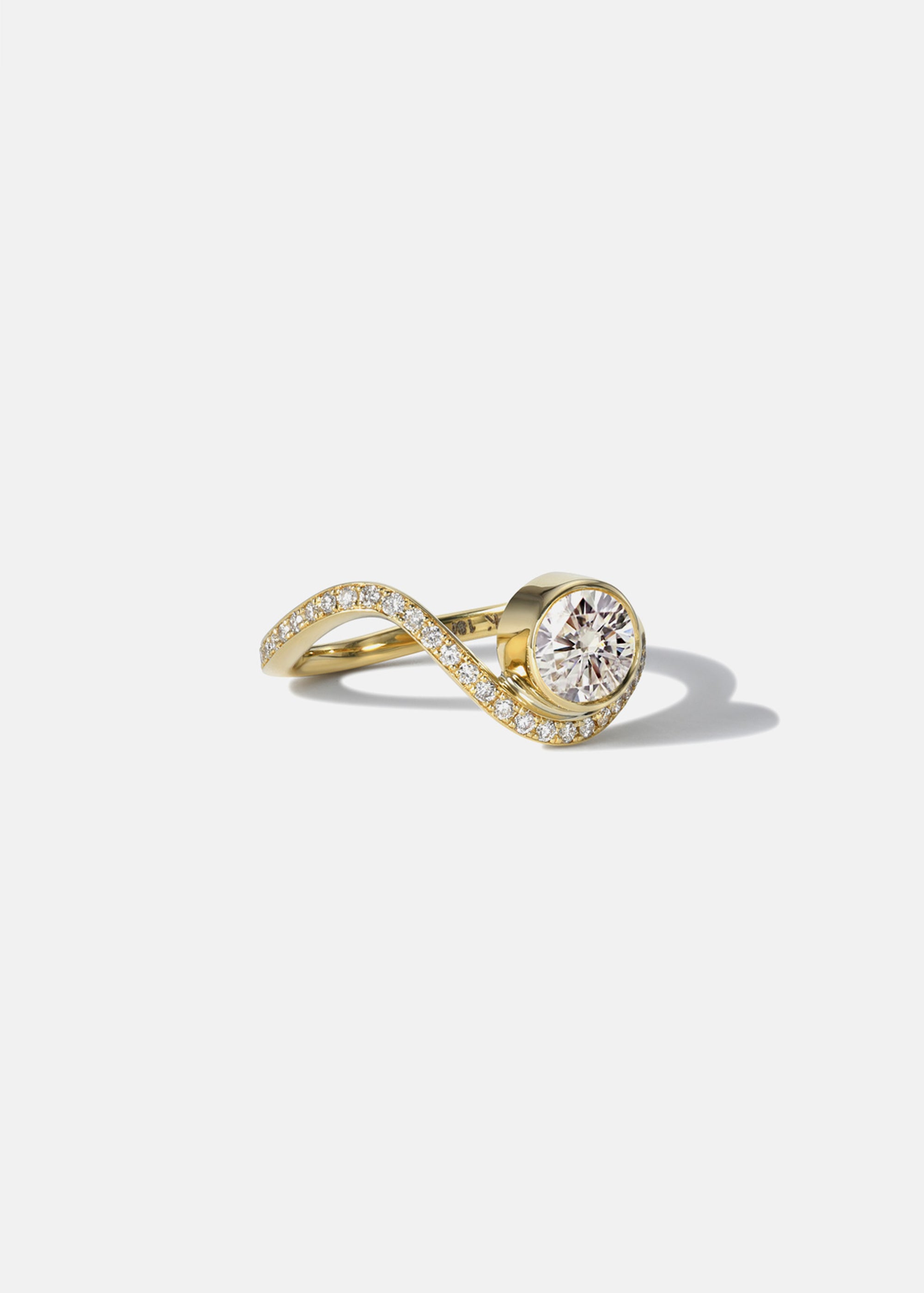 side view- a 18k yellow gold ring with a wavy band design with pavé diamonds featuring a round brilliant-cut center stone.