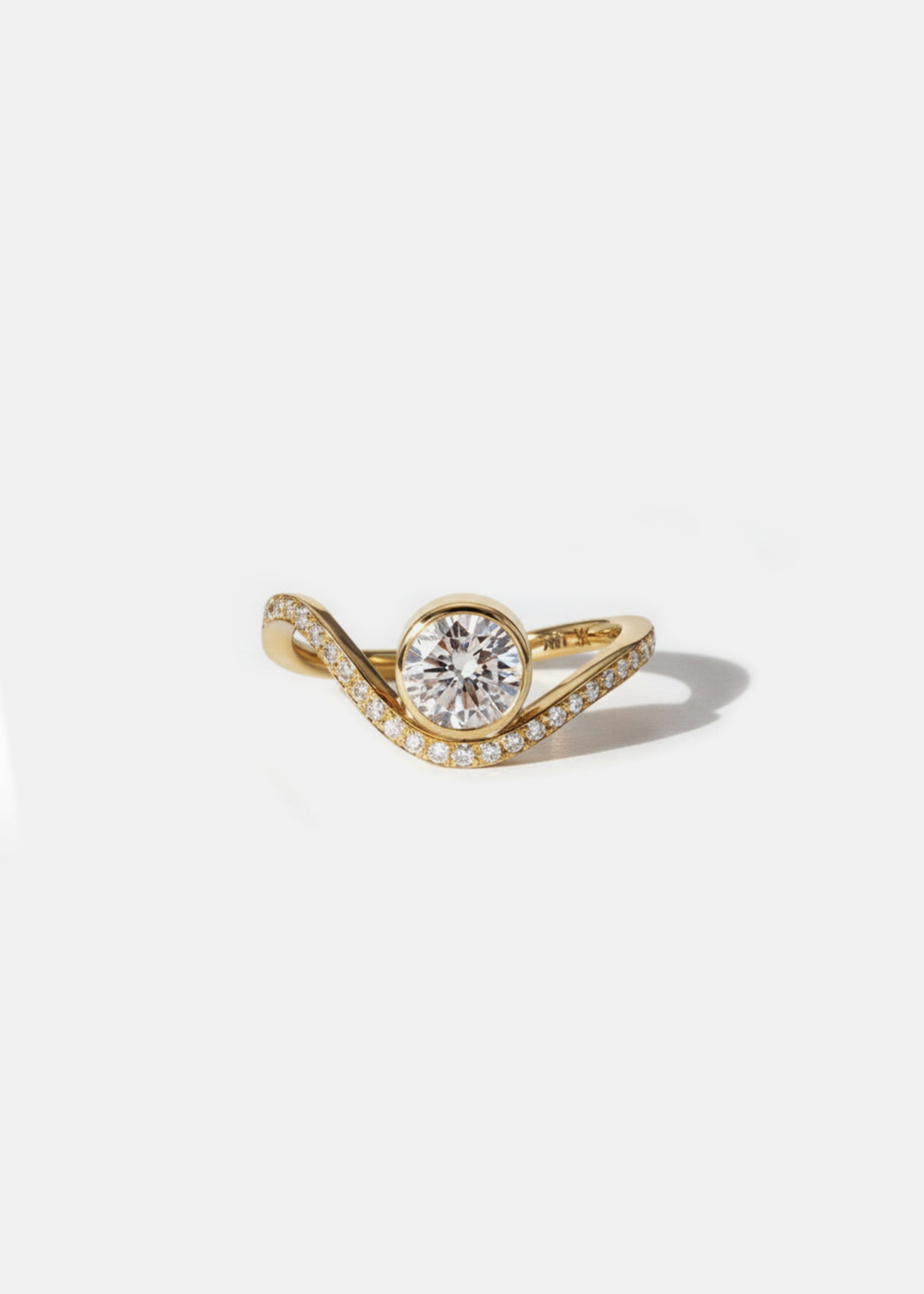 A 18k yellow gold ring with a wavy band design with pavé diamonds featuring a round brilliant-cut center stone.