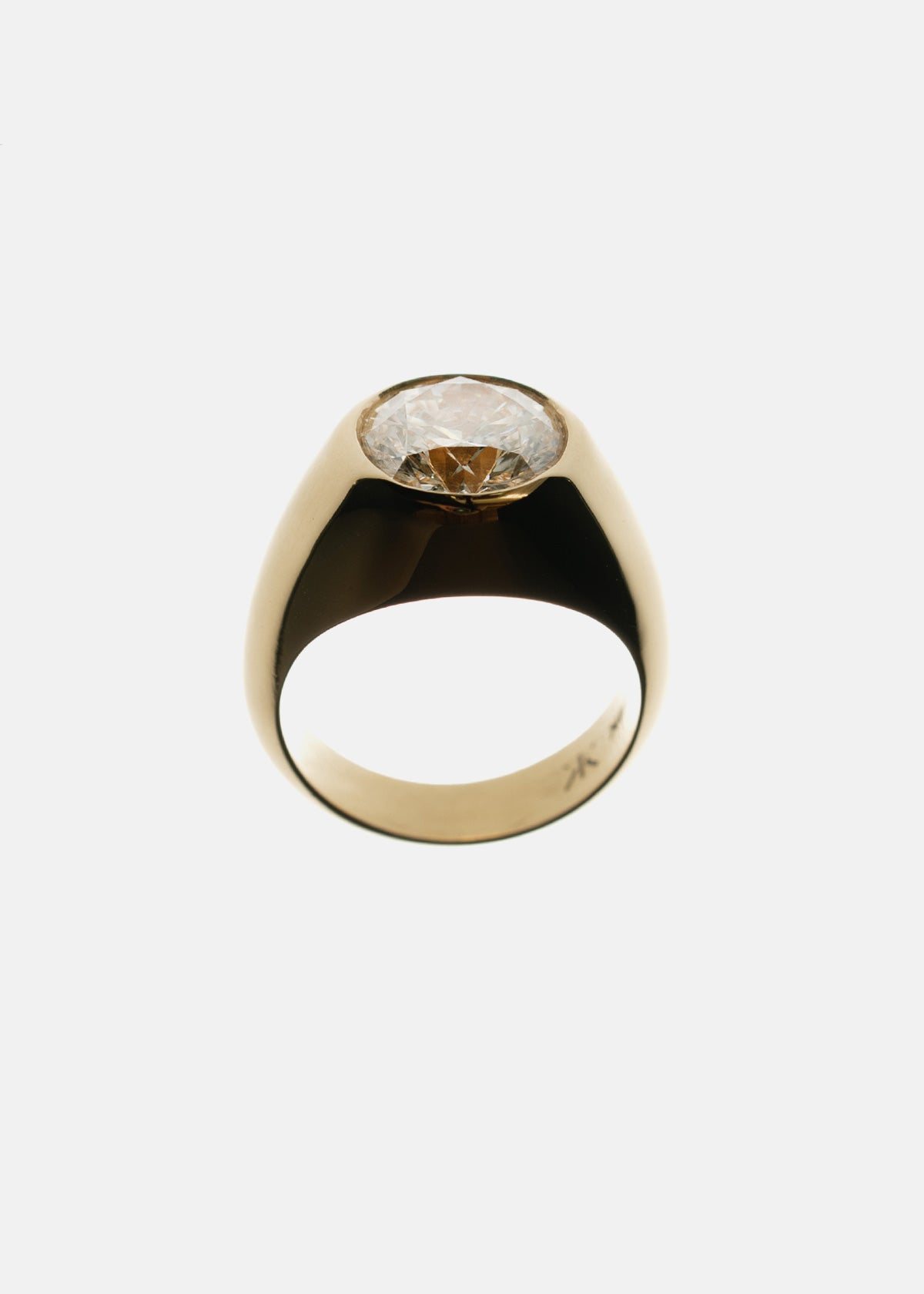 A tapering gold band with a oval cut diamond as center stone against a backlit background.