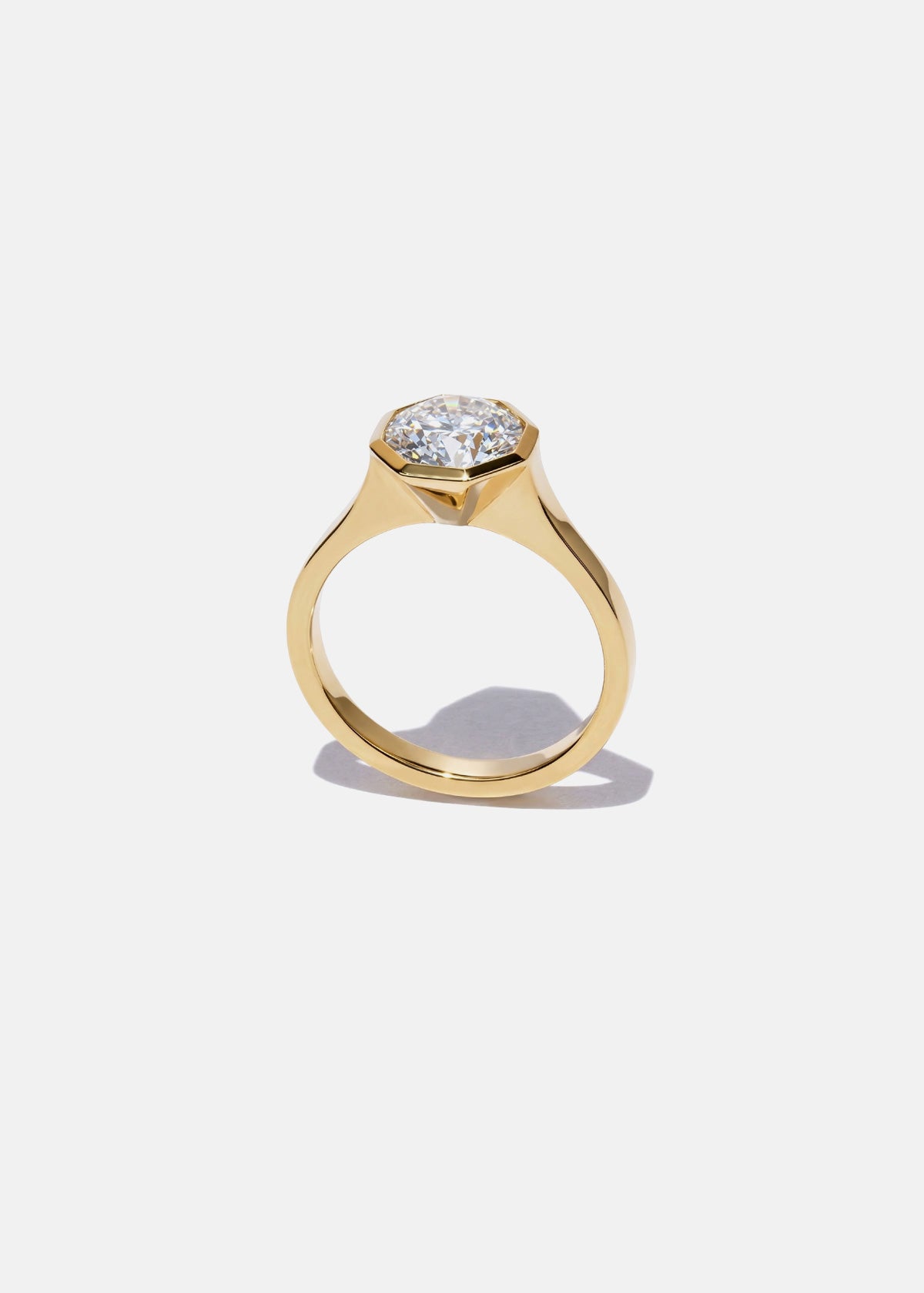 18k yellow gold architectural engagement ring with a round cut diamond in a thick, octagon bezel setting.