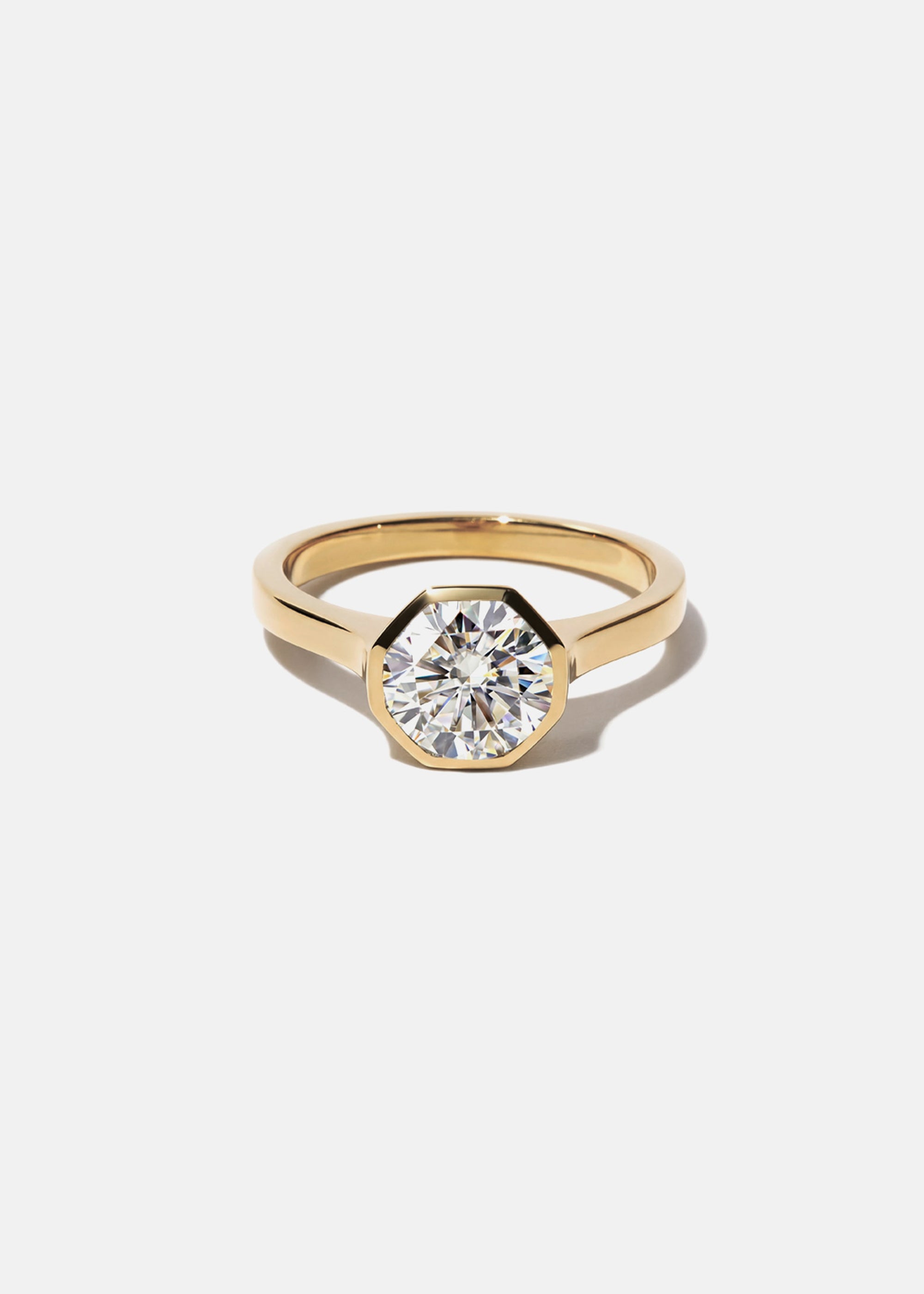 18k yellow gold architectural engagement ring with a round cut diamond in a thick, octagon bezel setting.
