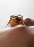 close up of 18k yellow gold architectural engagement ring with a round cut diamond in a thick, octagon bezel setting.