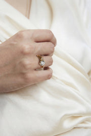 hand wearing a pairing of a 18k yellow gold architectural engagement ring with a round cut diamond in a thick, octagon bezel setting and a open band with a round cut diamond.