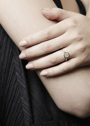 close up of a handing wearing 18k yellow gold architectural engagement ring with a round cut diamond in a thick, octagon bezel setting.