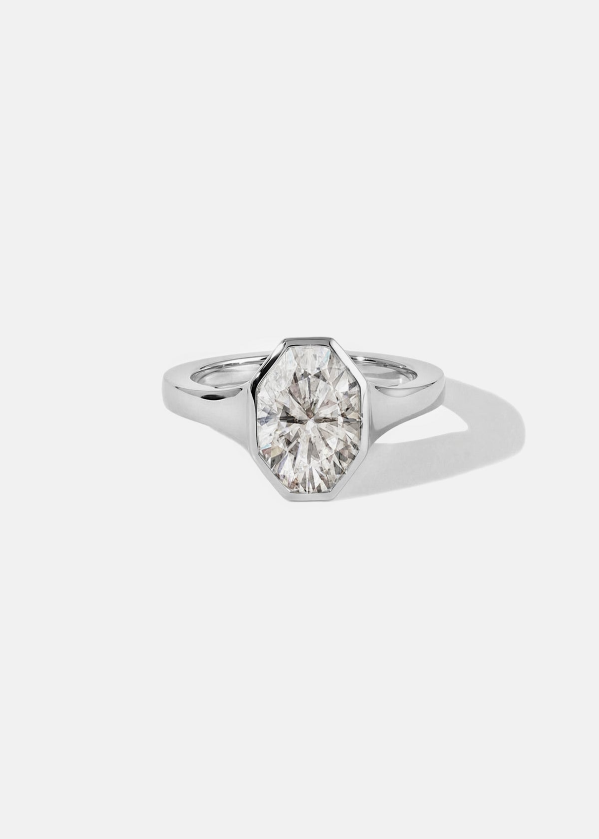18k white gold engagement ring featuring an oval cut diamond in a sculpted octagonal bezel frame.