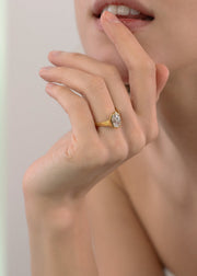 closeup of a hand wearing a 18k yellow gold engagement ring featuring an oval cut diamond in a sculpted octagonal bezel frame.