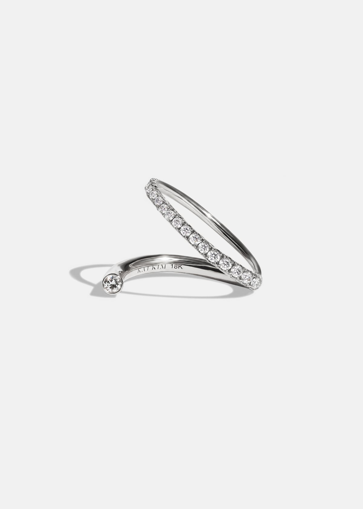 18k white gold wrapping ring with an accent floating diamond and a subtle tilted band with pavé diamonds.