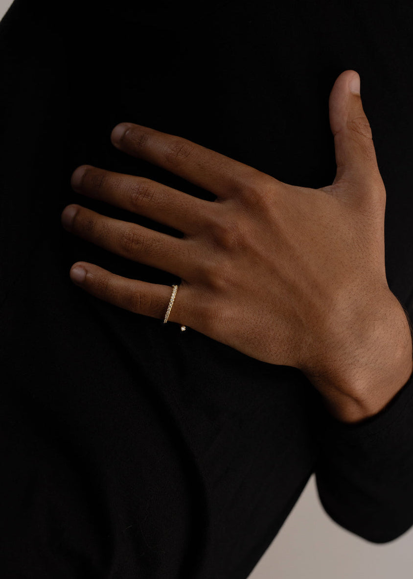 hand wearing 18k yellow gold wrapping ring with an accent floating diamond and a subtle tilted band with pavé diamonds on the pinky finger.