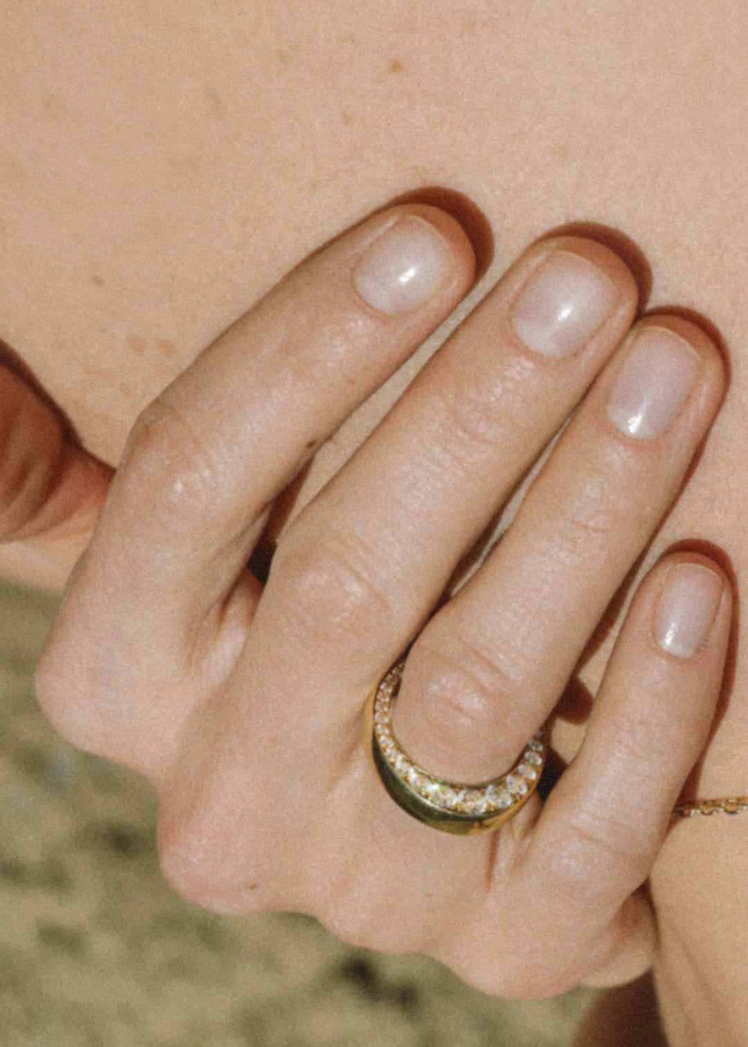 Close-up of a hand wearing a gold ring with a tapering of diamonds.