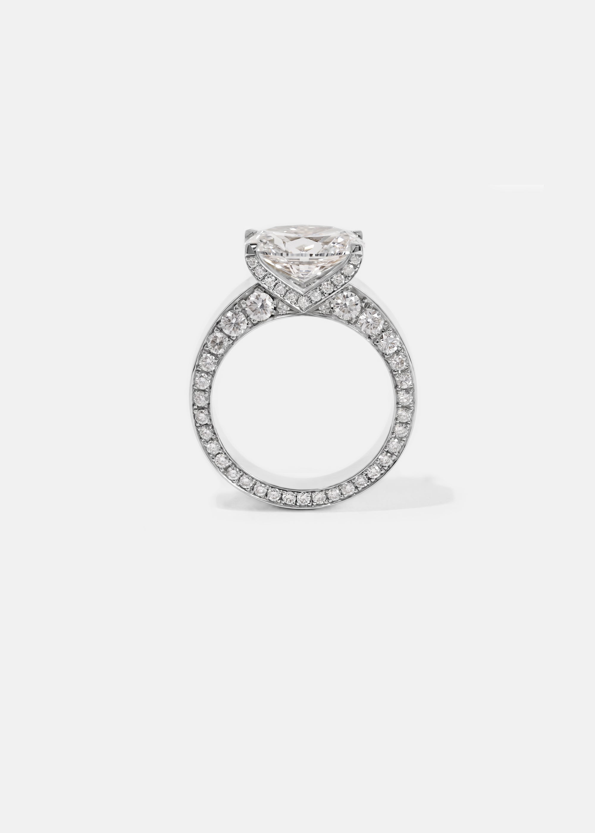 A 18k white gold ring featuring a oval cut diamond center stone and pavé-set diamonds along the shank with tapering diamonds along the band