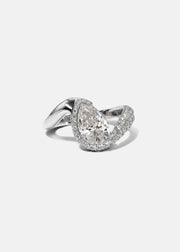  18k white gold ring featuring a pear-cut diamond in a curved, wave-like setting with pavé diamonds around the center stone