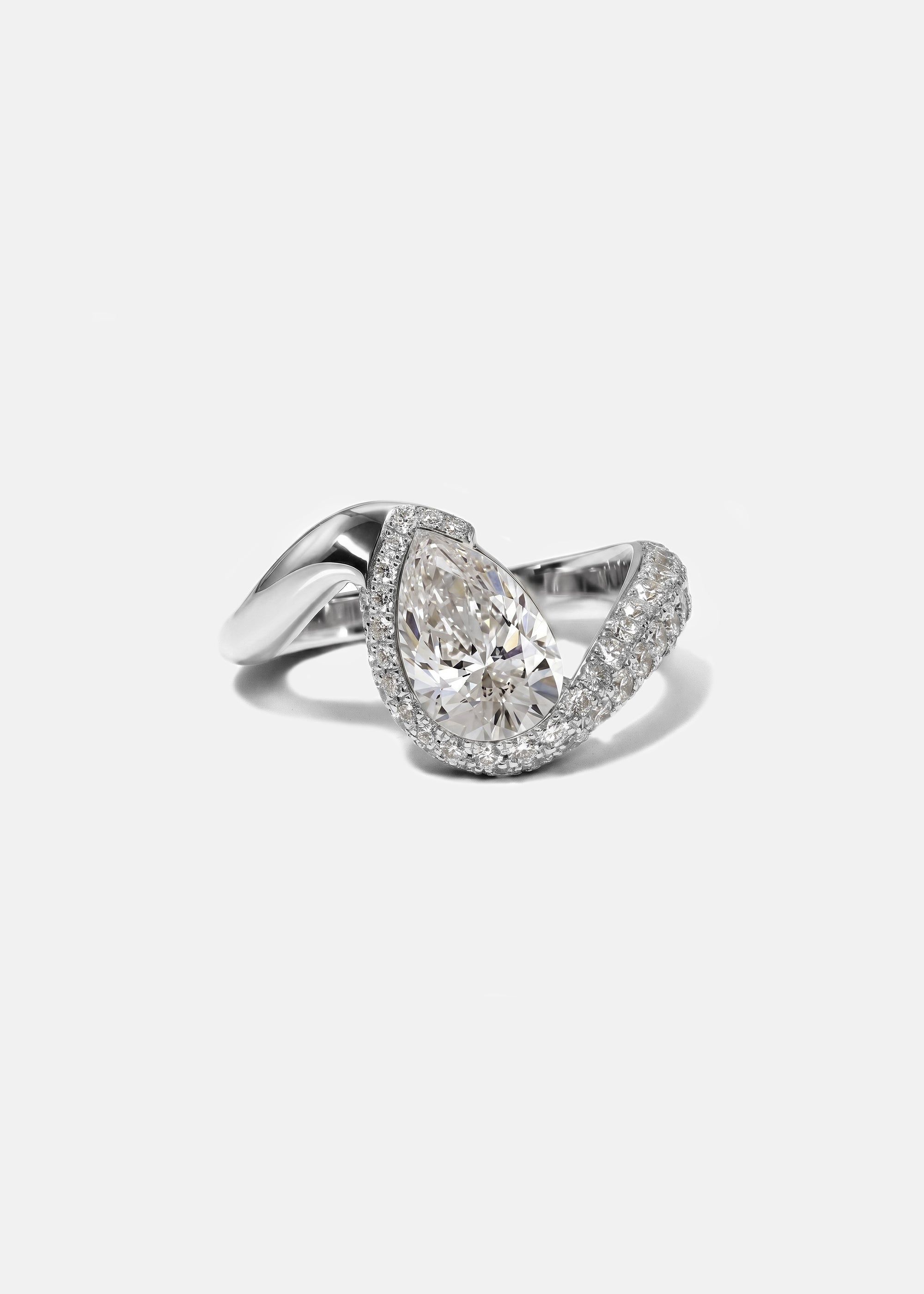  18k white gold ring featuring a pear-cut diamond in a curved, wave-like setting with pavé diamonds around the center stone
