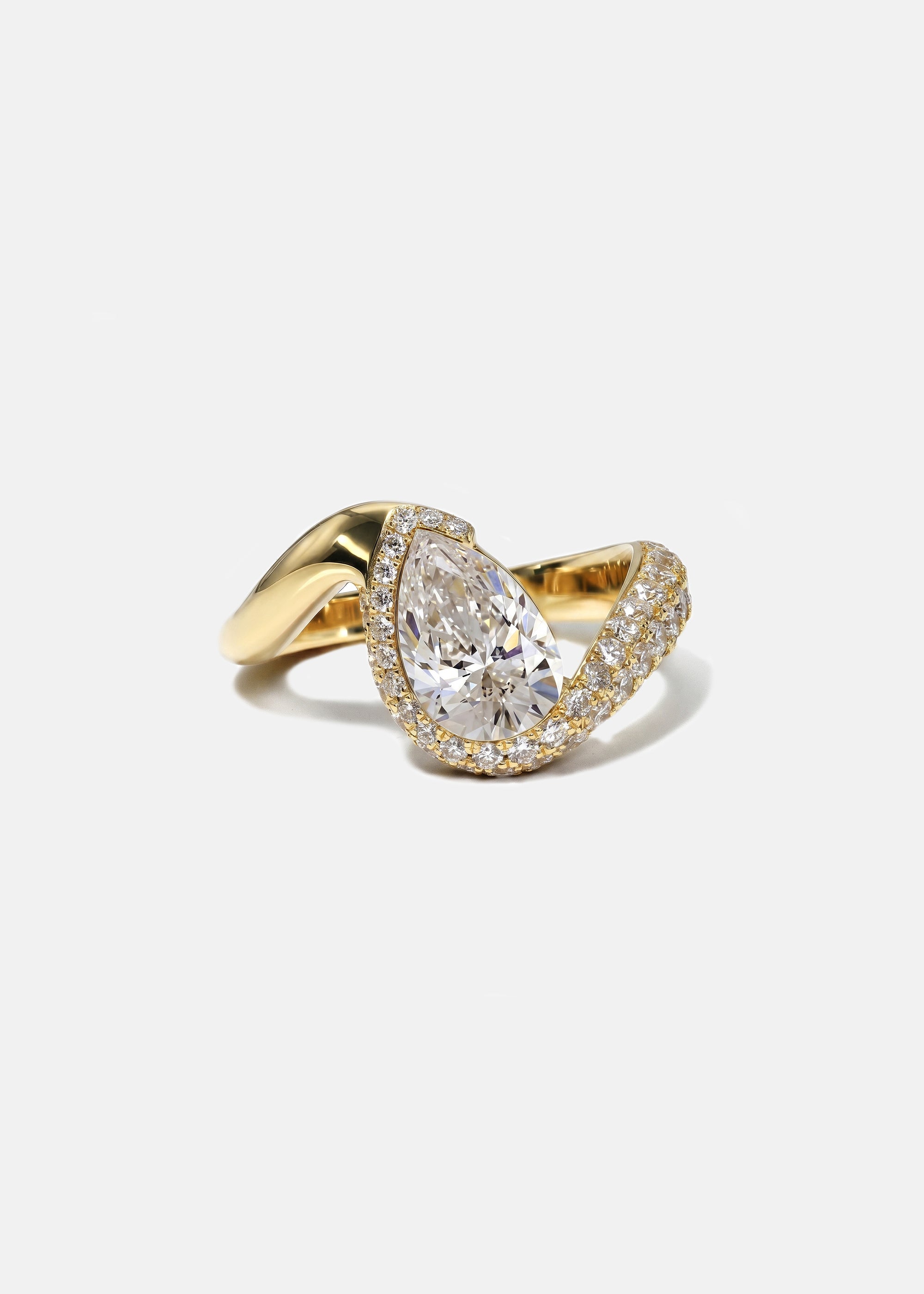  18k yellow gold ring featuring a pear-cut diamond in a curved, wave-like setting with pavé diamonds around the center stone