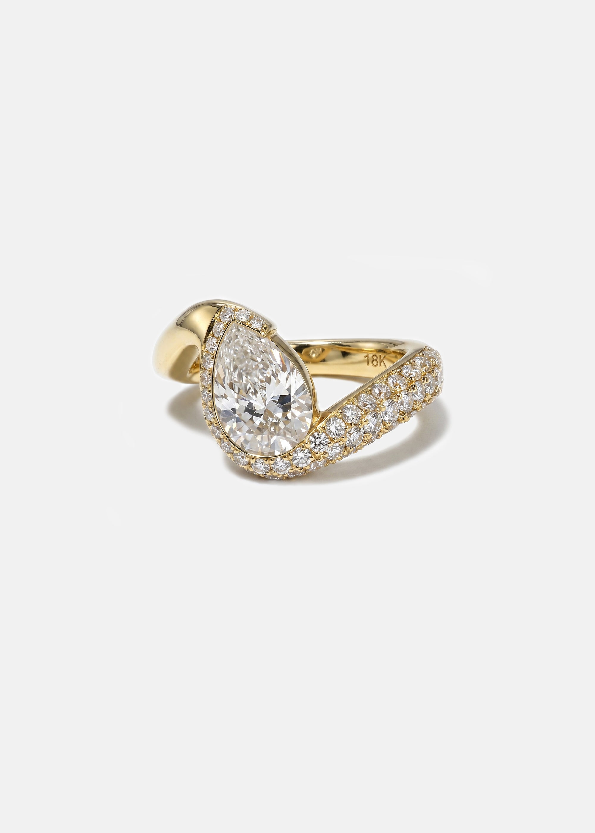 side view of  18k yellow gold ring featuring a pear-cut diamond in a curved, wave-like setting with pavé diamonds around the center stone