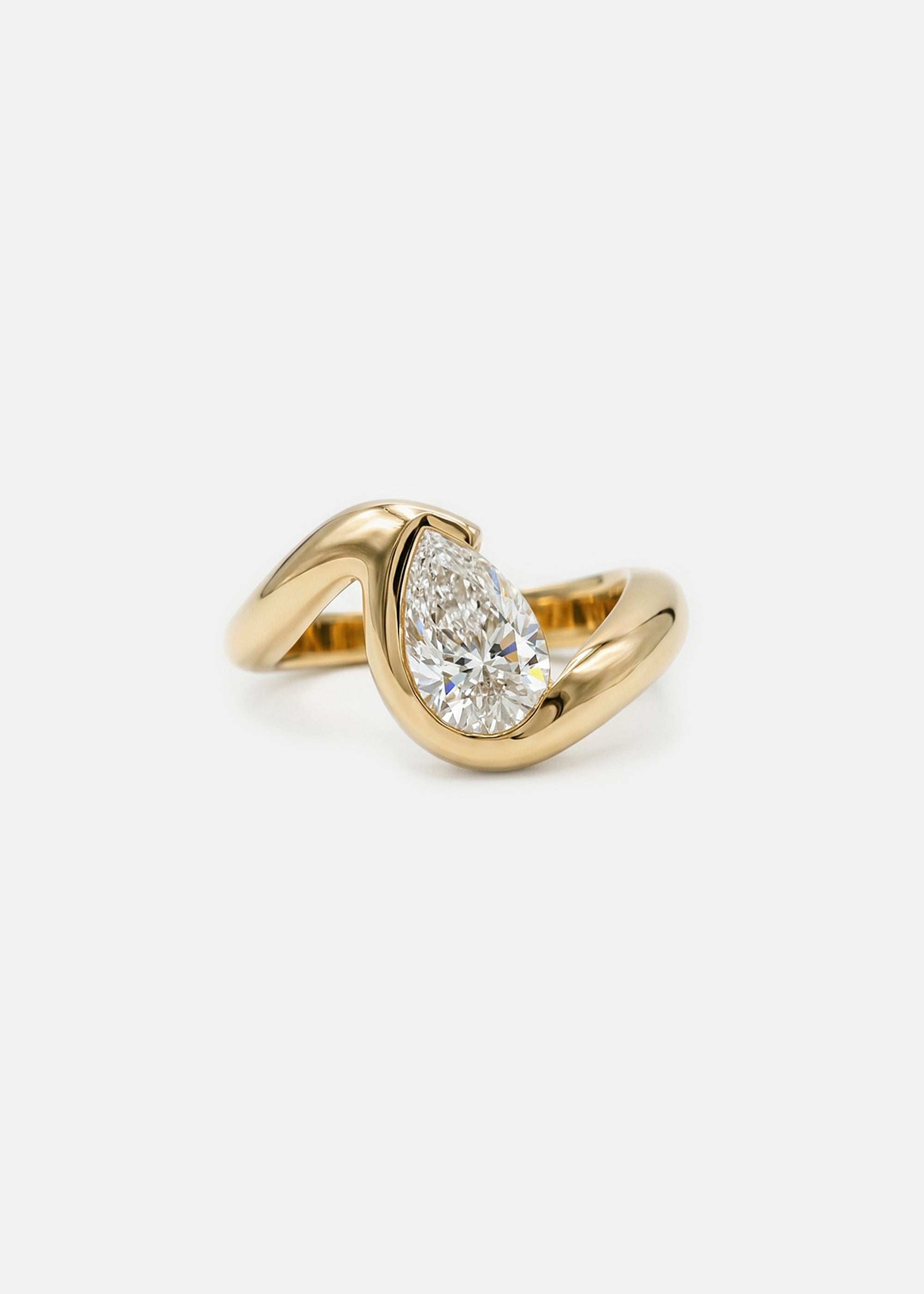 18k yellow gold ring featuring a pear-cut diamond in a curved, wave-like setting.