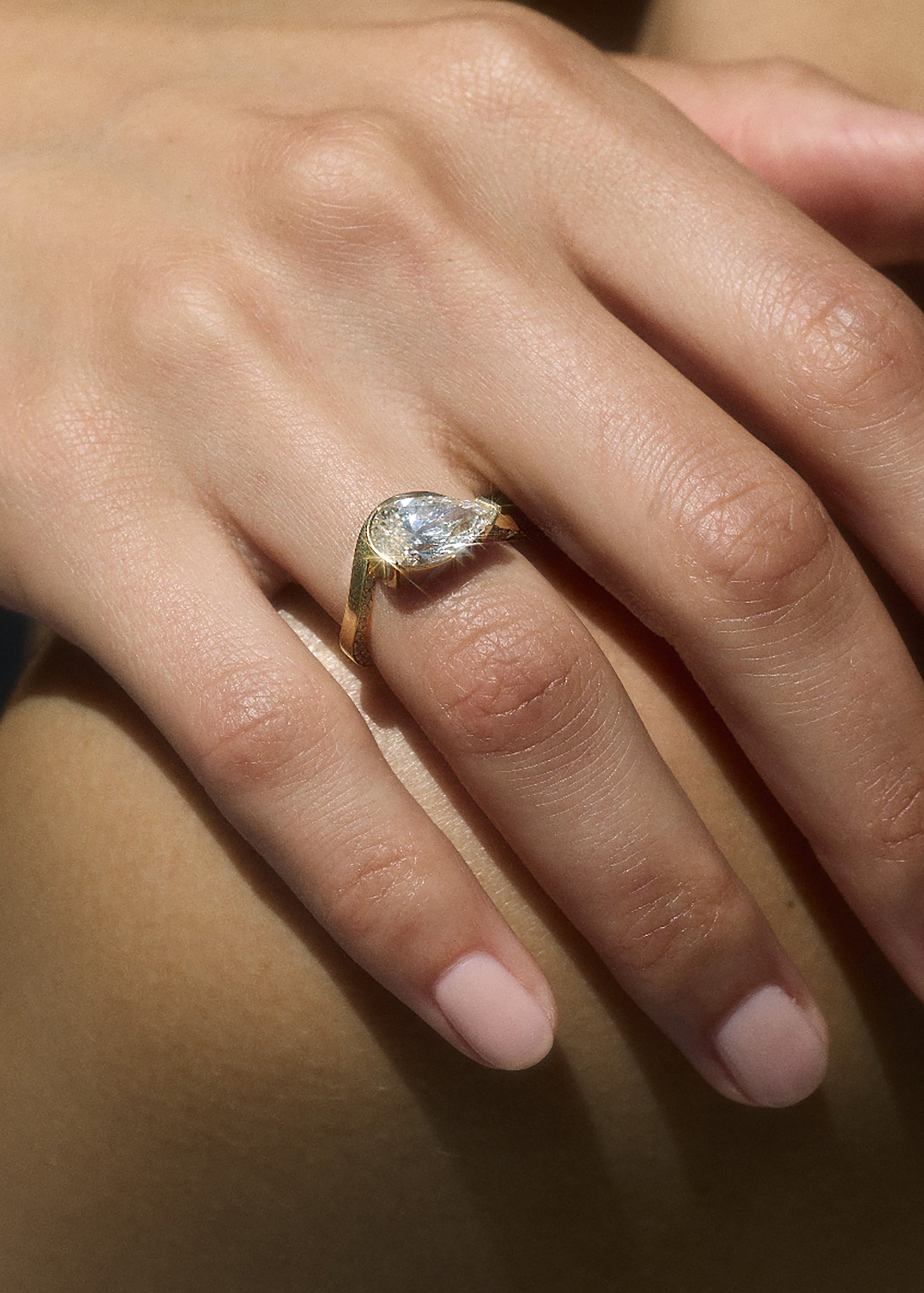model wearing the 18k yellow gold ring- wave band with pavé diamonds- pear cut diamond