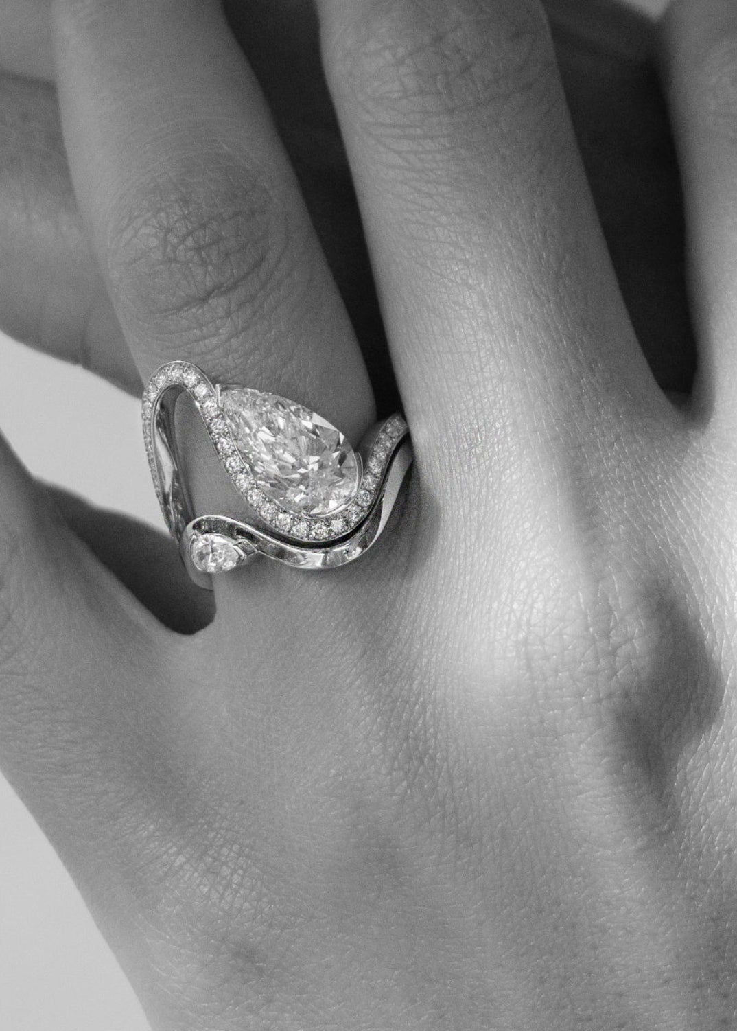 model wearing a gold wave pavé band with a pear cut diamond paired with a gold wave band with a small pear cut diamond-18K yellow gold