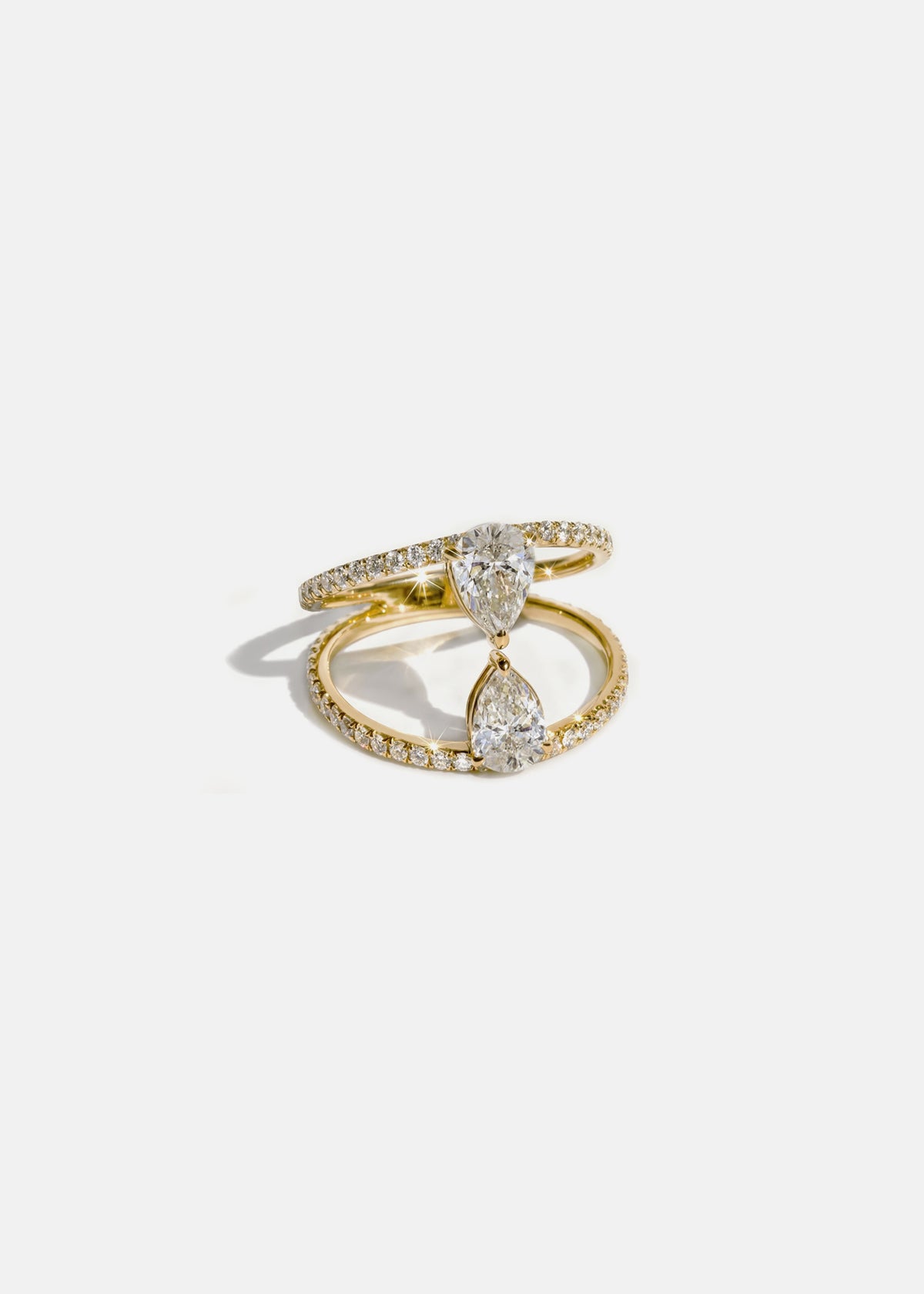 18k yellow gold dual engagement ring with two touching pear-cut diamonds facing opposite directions, with pavé diamonds along the band.