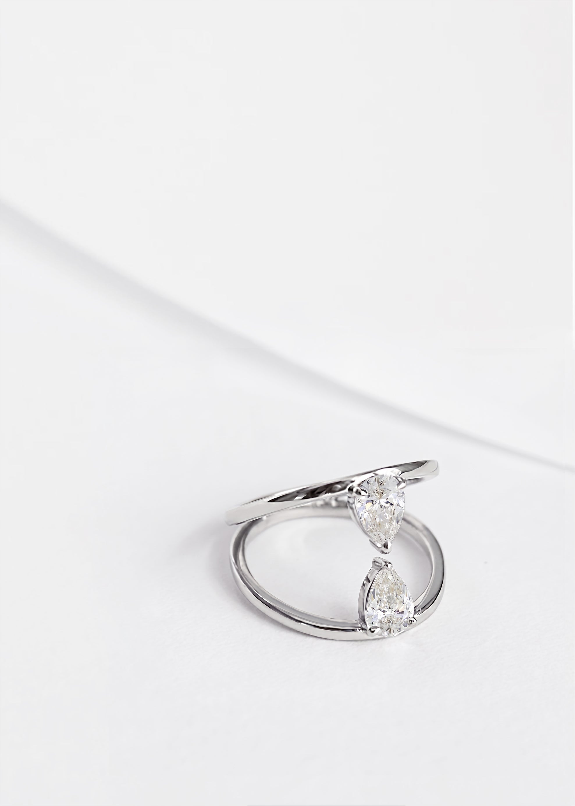18k white gold engagement ring with two touching pear-cut diamonds facing opposite directions.