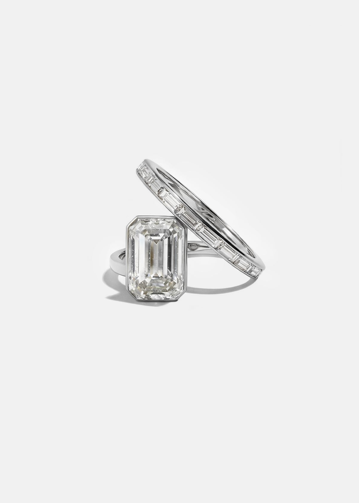 18k white gold bypass ring featuring a floating emerald cut diamond and tapering channel of baguettes band.