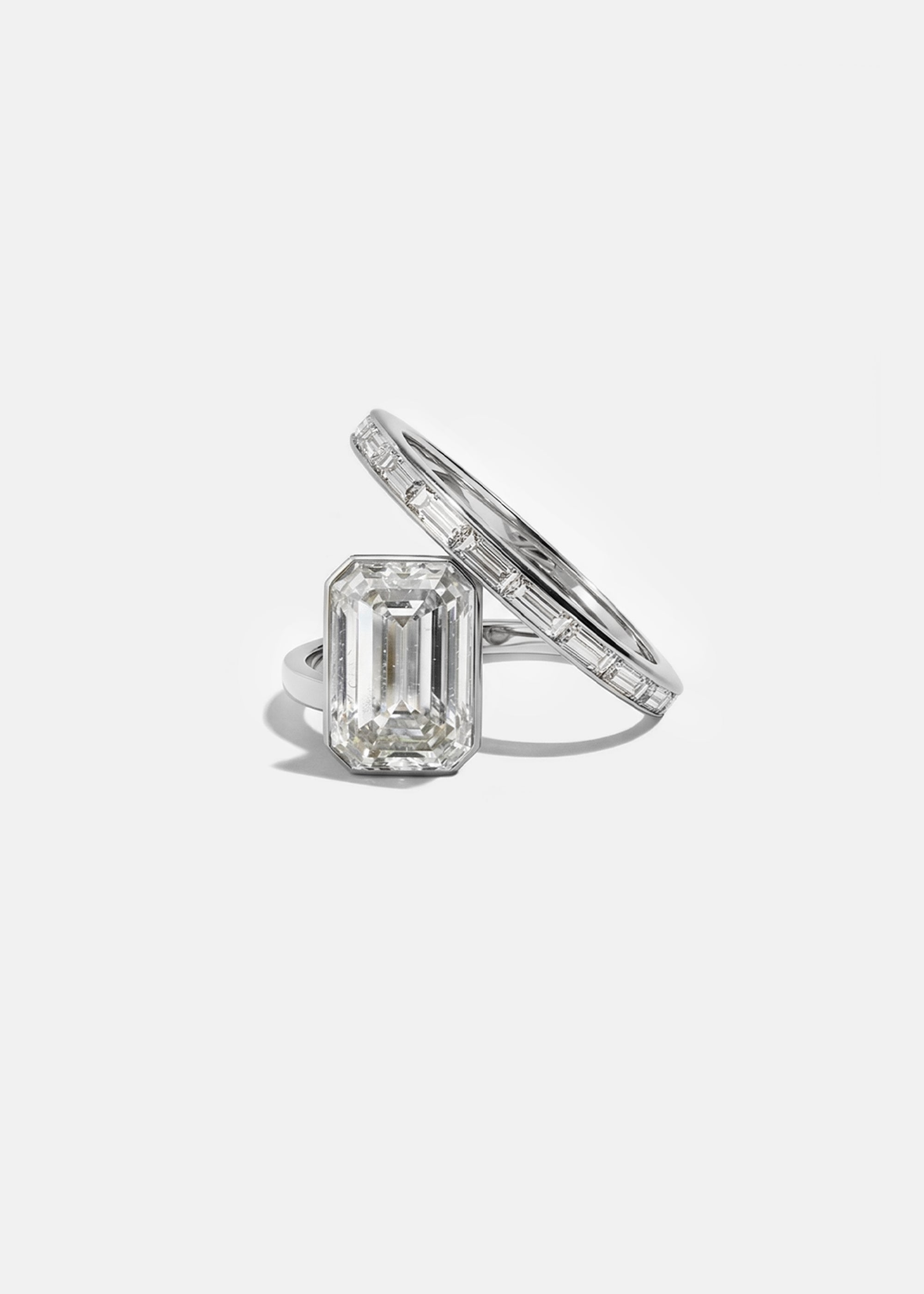 18k white gold bypass ring featuring a floating emerald cut diamond and tapering channel of baguettes band.