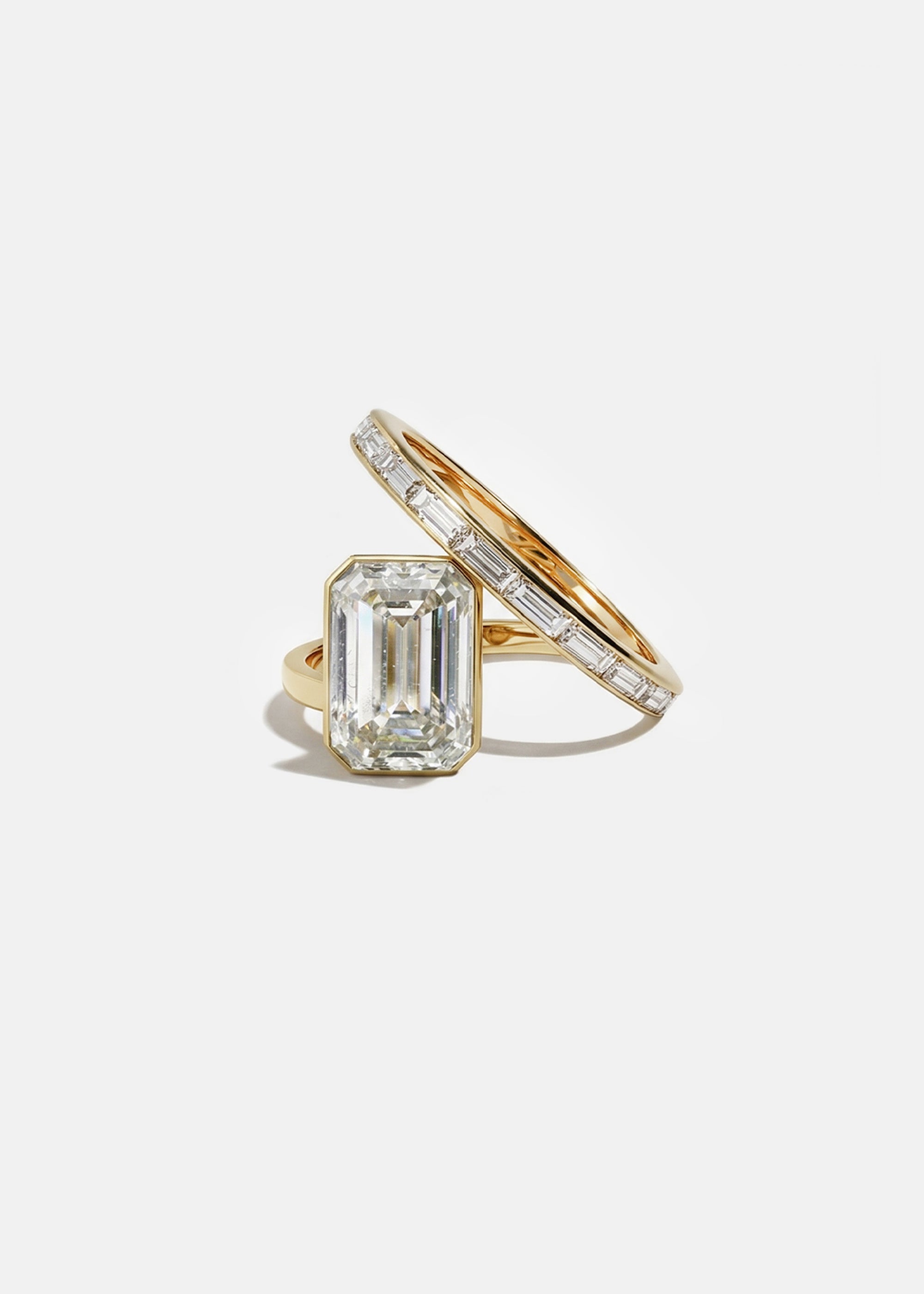 18k yellow gold bypass ring featuring a floating emerald cut diamond and tapering channel of baguettes band.