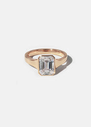 a 18k rose gold ring with a emerald cut diamond center stone