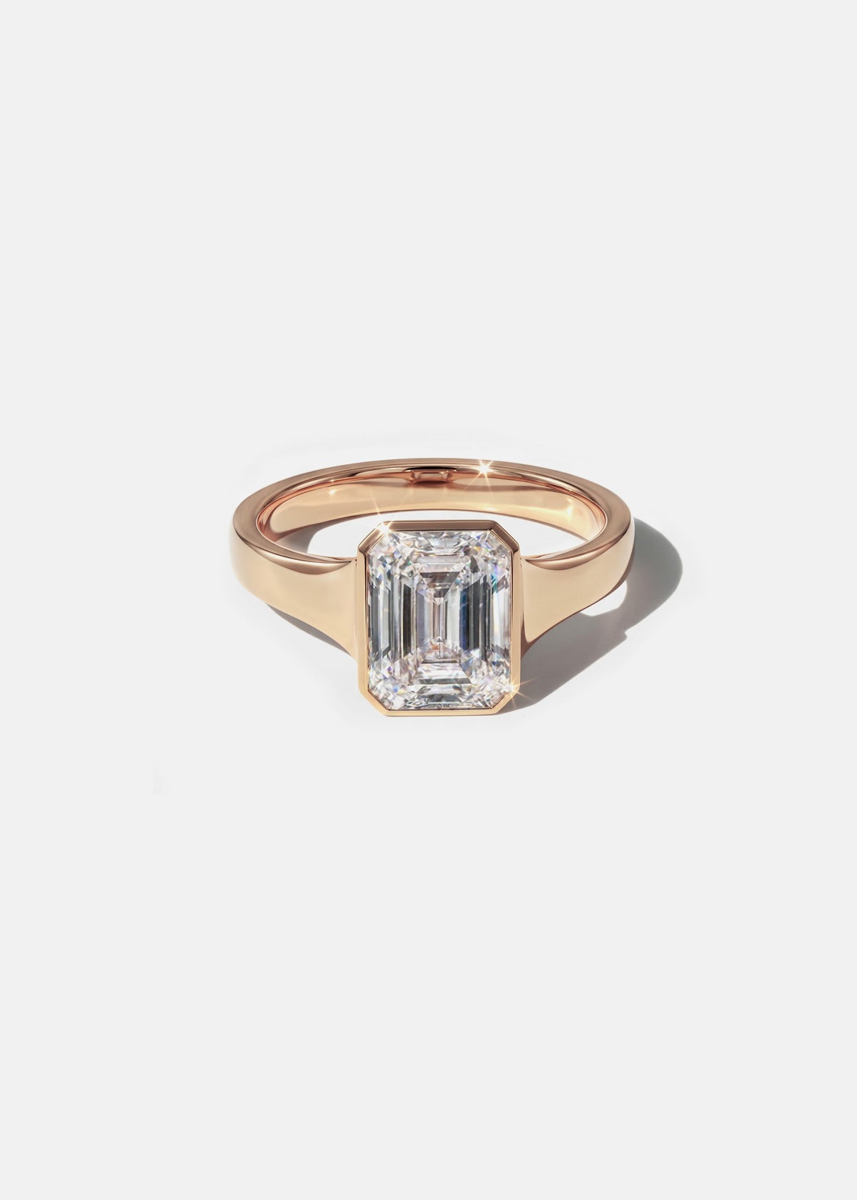 a 18k rose gold ring with a emerald cut diamond center stone