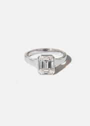 a 18k white gold ring with a emerald cut diamond center stone