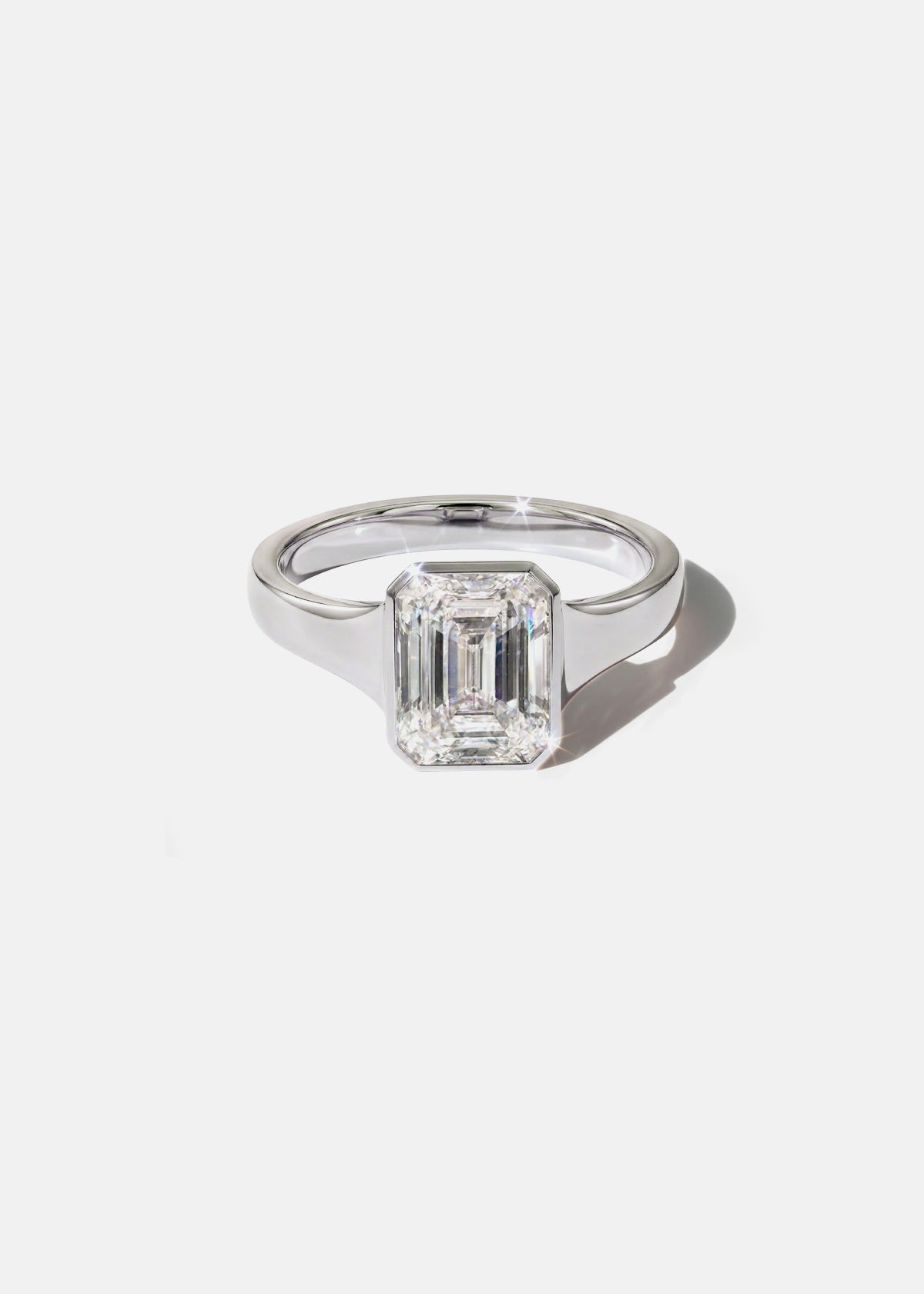 a 18k white gold ring with a emerald cut diamond center stone