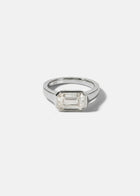 a 18k white gold ring with a east west emerald cut diamond as the center stone