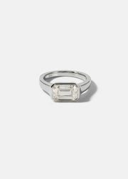 a 18k white gold ring with a east west emerald cut diamond as the center stone