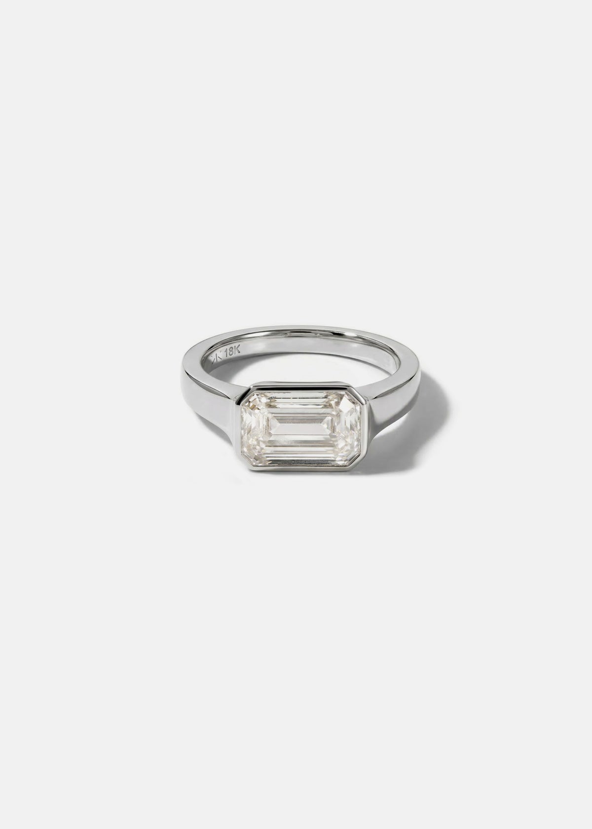 a 18k white gold ring with a east west emerald cut diamond as the center stone