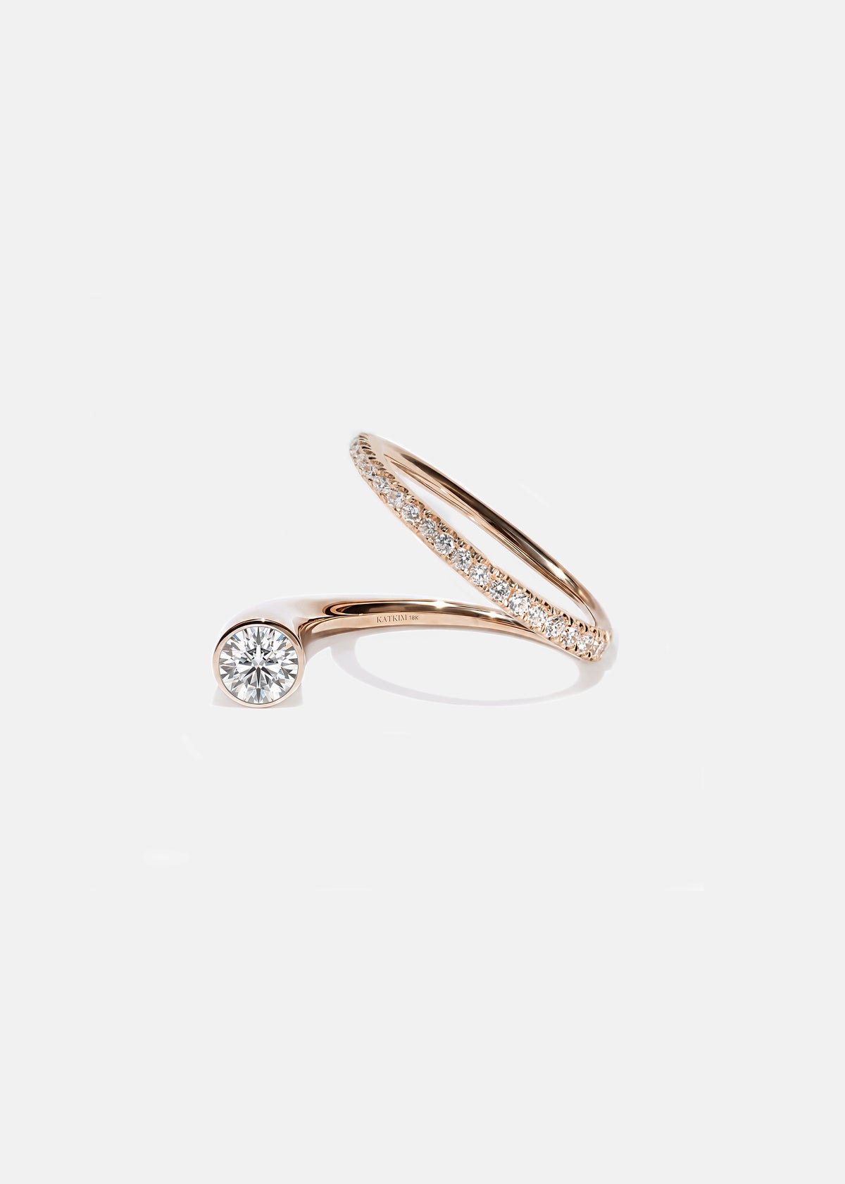 18k rose gold sculptural bypass ring featuring a floating round cut diamond accented by an unexpected tilted band silhouette with pavé diamonds.
