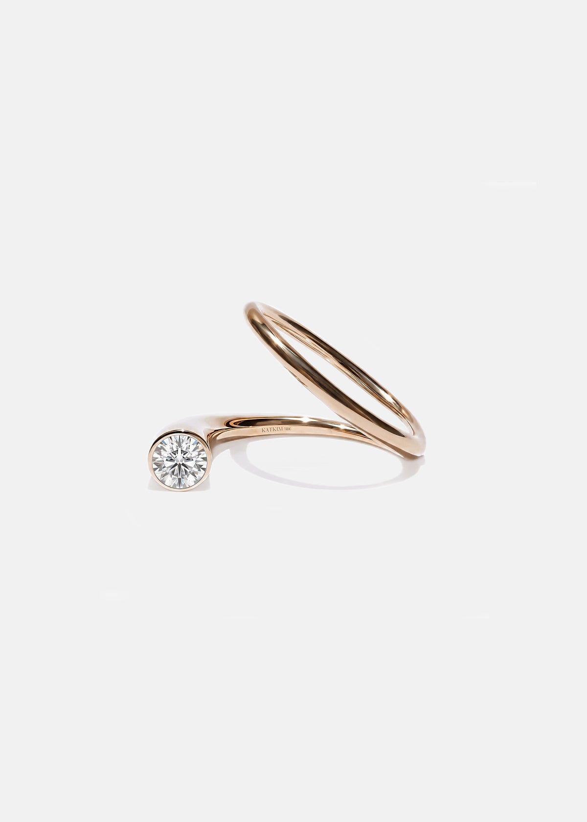 18k rose gold sculptural bypass ring featuring a floating round cut diamond accented by an unexpected tilted band silhouette