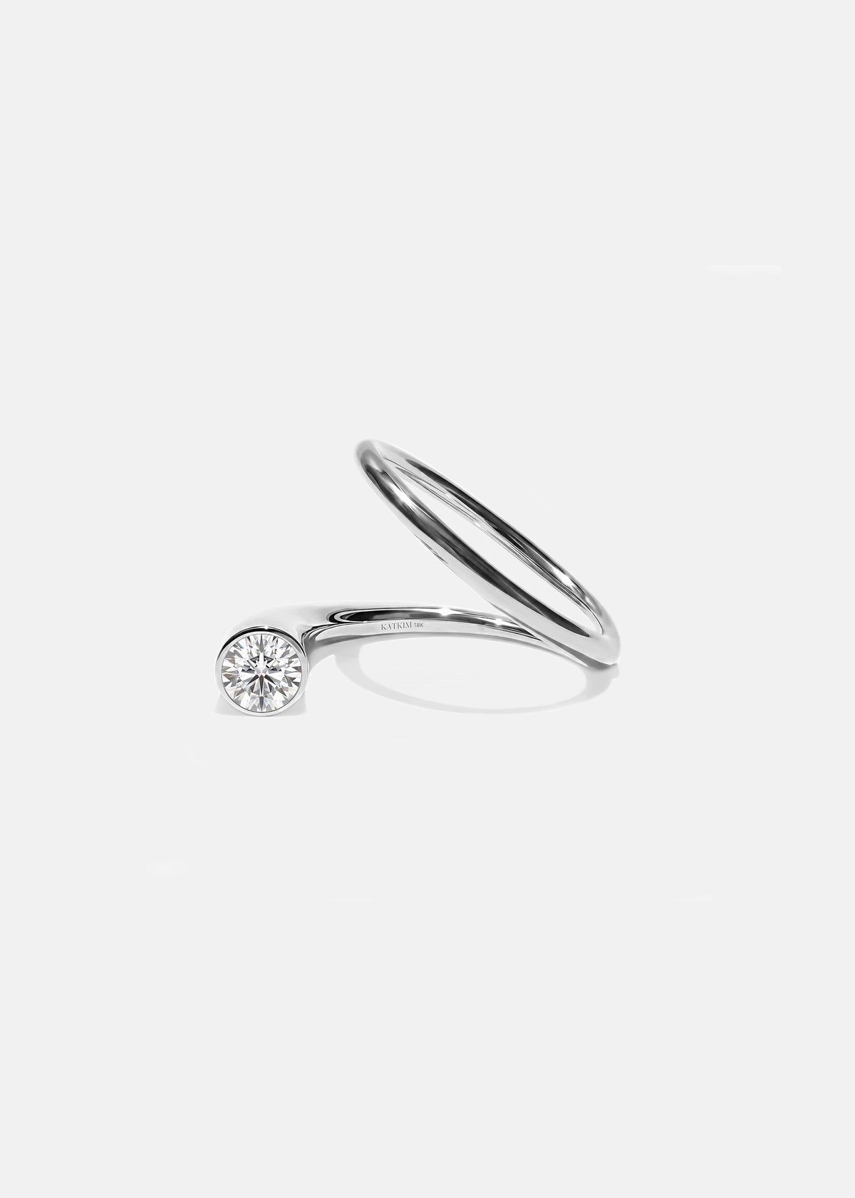 18k white gold sculptural bypass ring featuring a floating round cut diamond accented by an unexpected tilted band silhouette