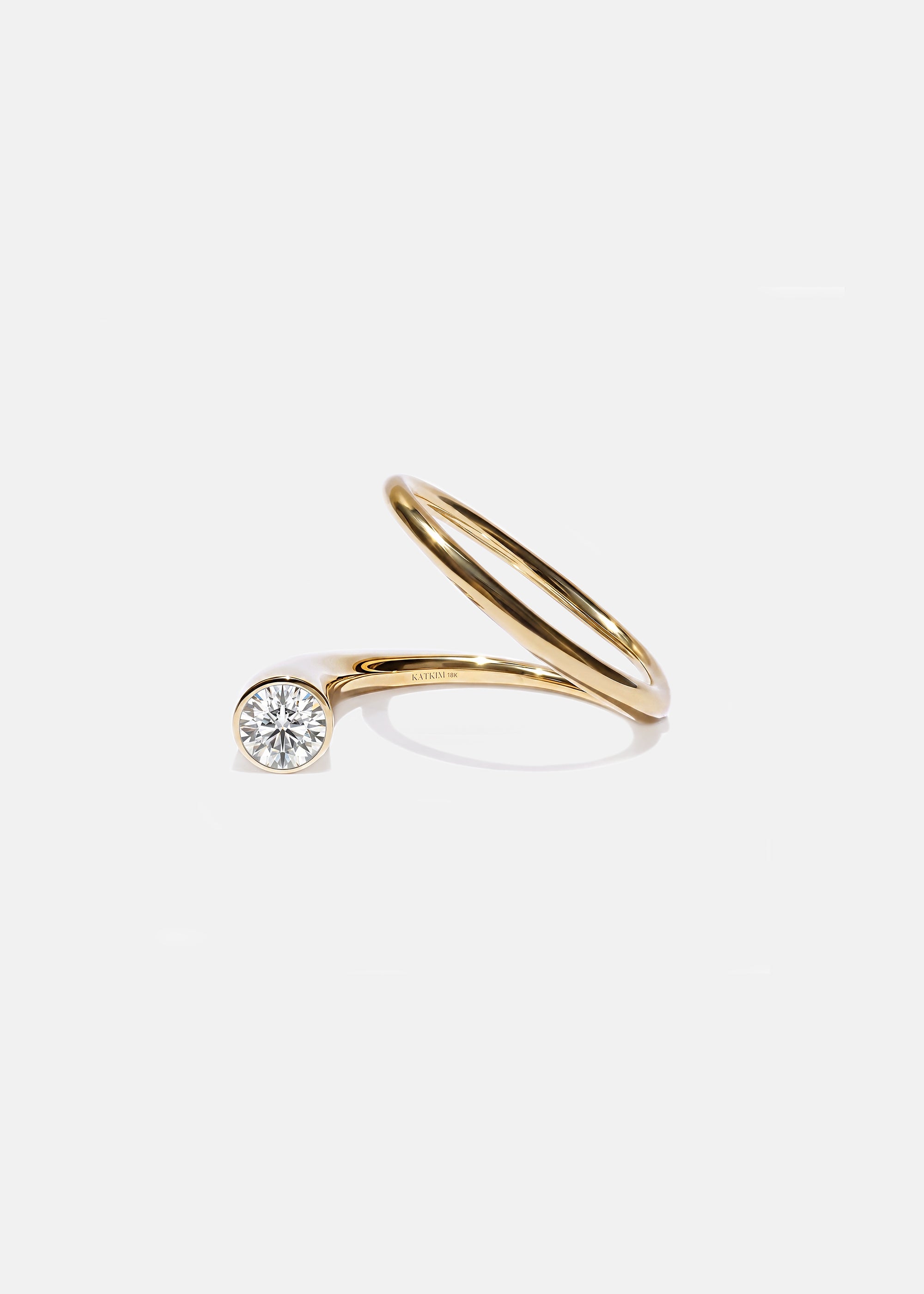 18k yellow gold sculptural bypass ring featuring a floating round cut diamond accented by an unexpected tilted band silhouette