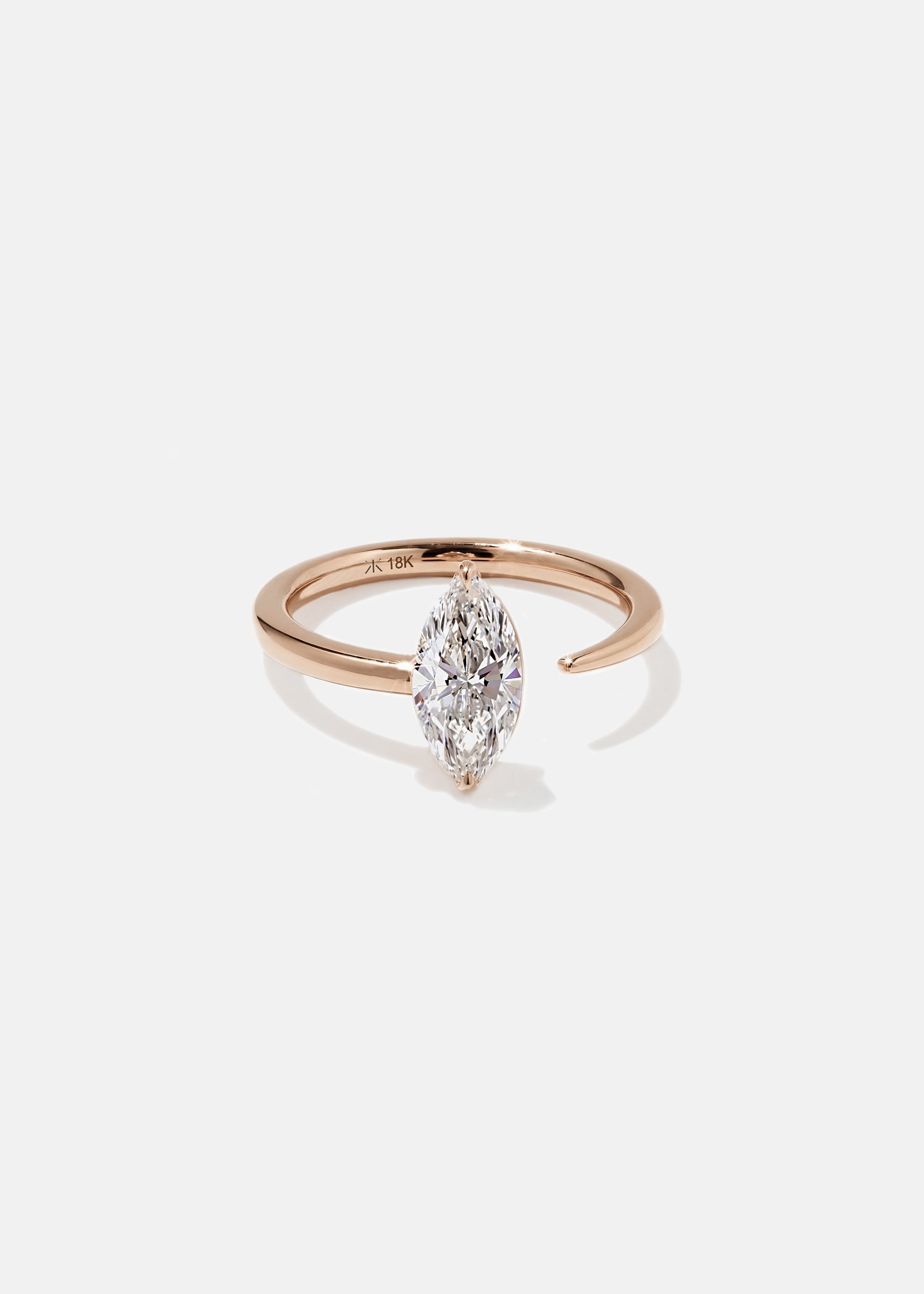 18k rose gold engagement ring with a prong-set marquise diamond anchored on a fluid, tapering open band