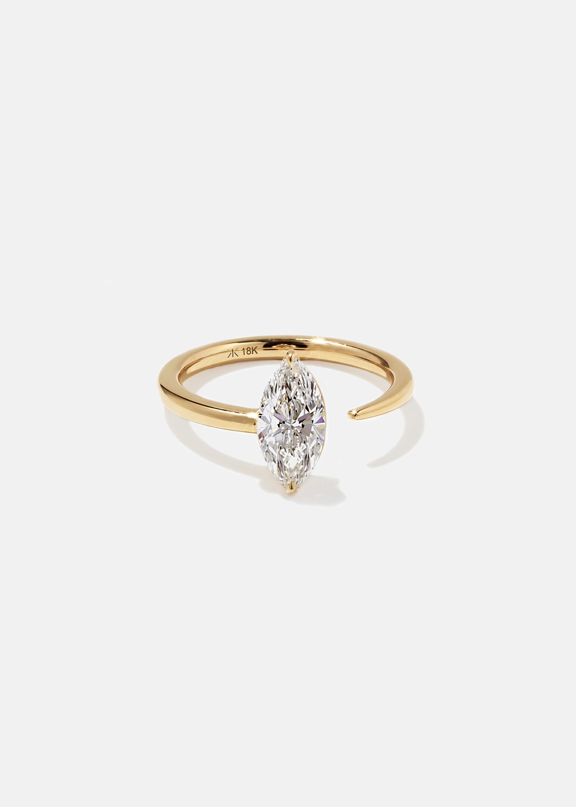 18k yellow gold engagement ring with a prong-set marquise diamond anchored on a fluid, tapering open band.