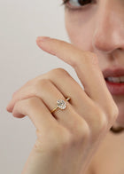 close up of a hand wearing 18k yellow gold Brilliant Crescendo Ring with a floating oval diamond on a tapered open band on her ring finger.