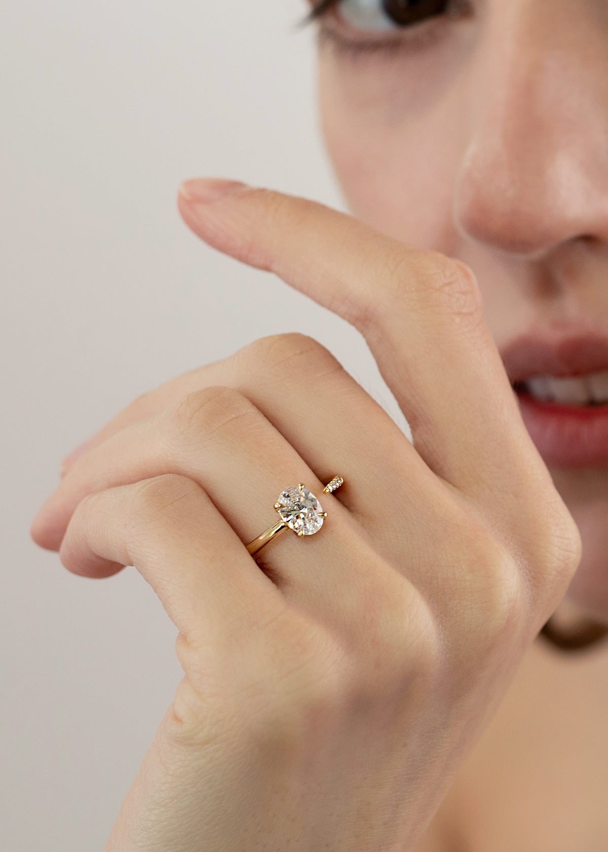 close up of a hand wearing 18k yellow gold Brilliant Crescendo Ring with a floating oval diamond on a tapered open band on her ring finger.