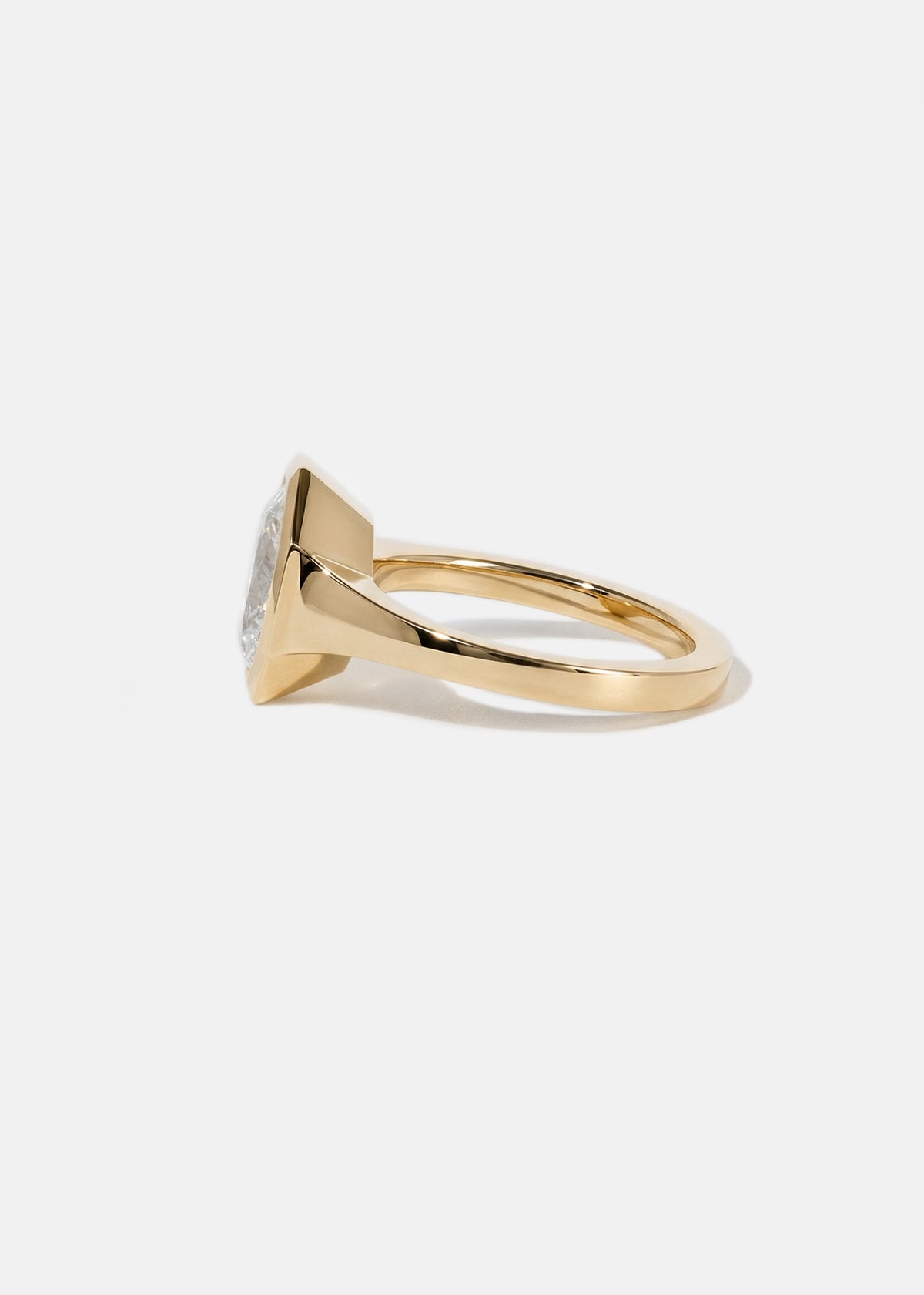side view of a tapering gold band with a thick octagon bezel setting of a oval cut diamond.