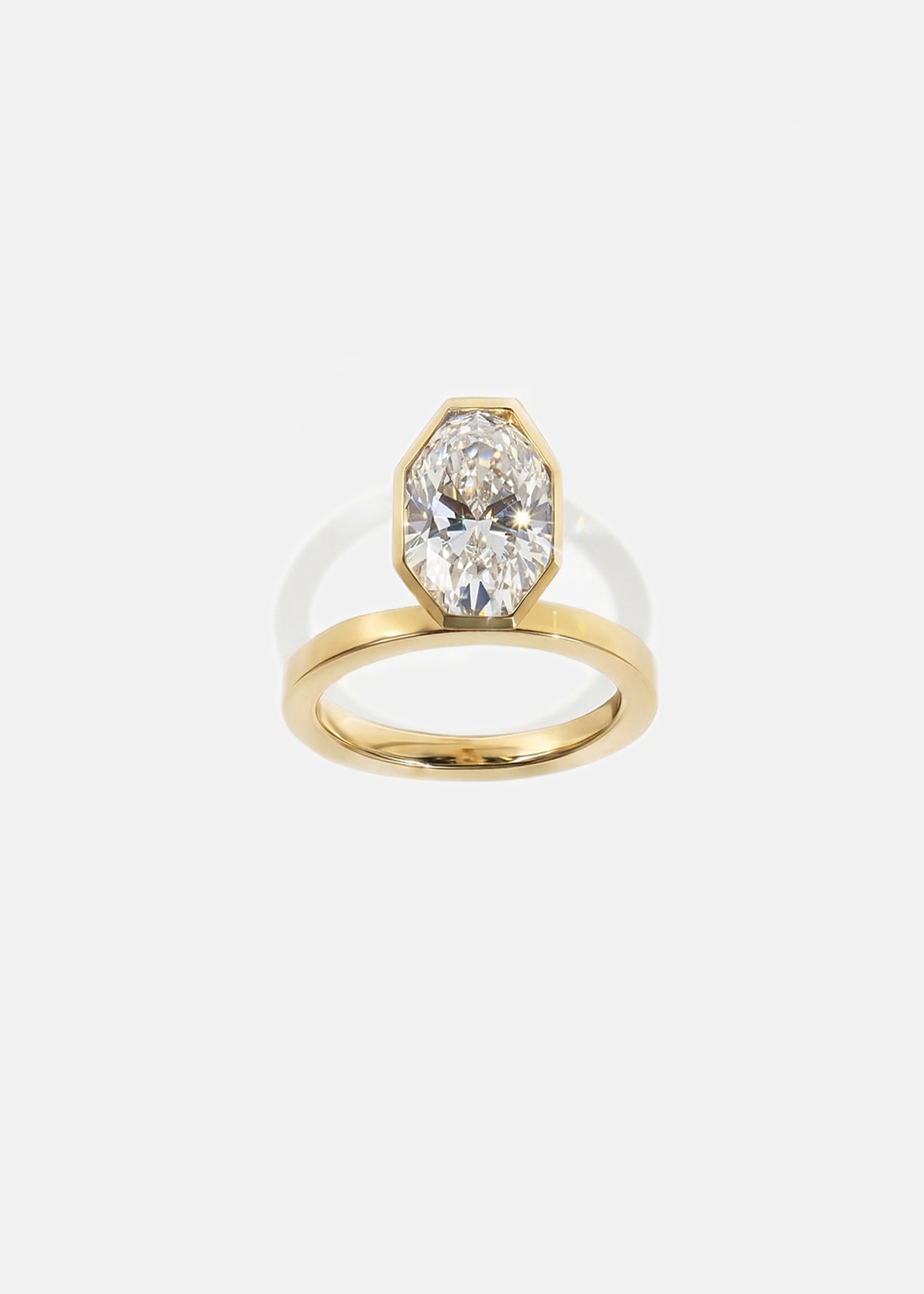 18k yellow gold engagement ring featuring an elevated floating oval cut diamond in a sculpted octagon bezel setting